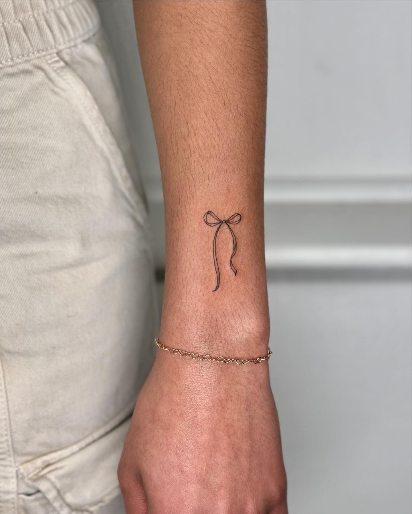 Bow fine line tattoo on the forearm by ๐๐๐๐๐๐๐