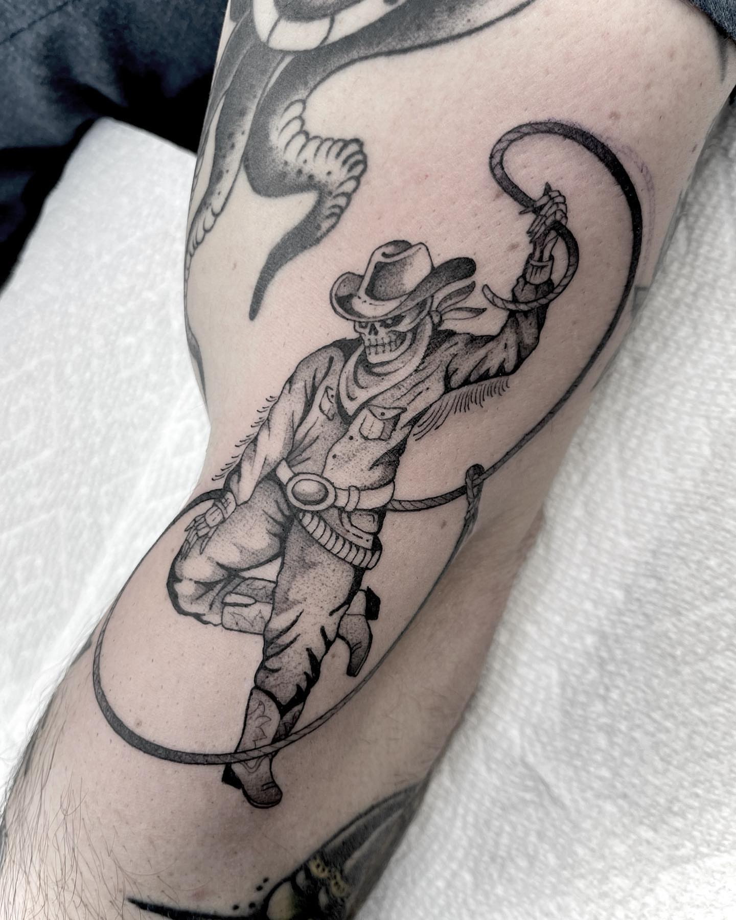 Cowboy skeleton with lasso black and grey tattoo on the forearm by Kelsi Steffensen