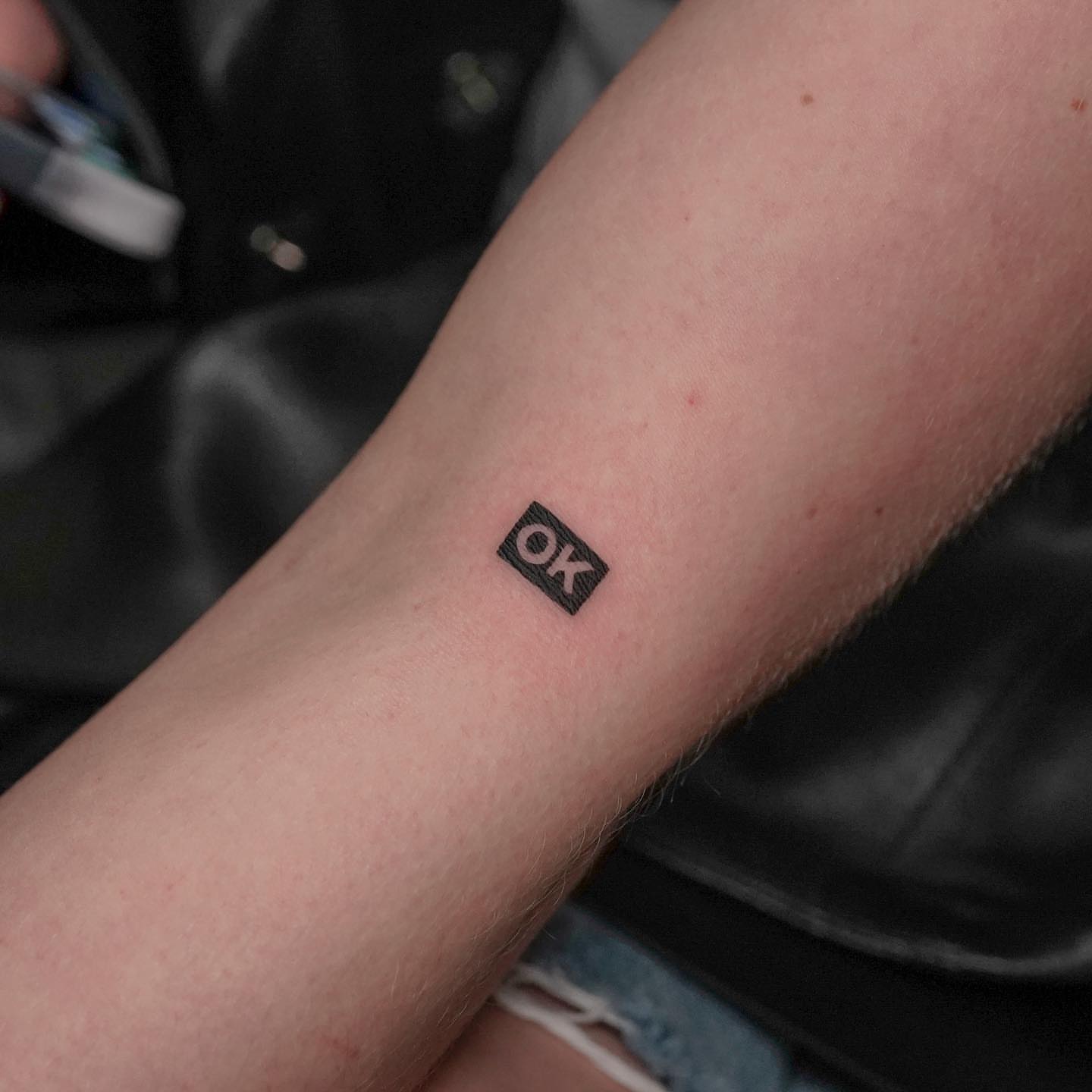 OK lettering script tattoo on the forearm by eddie chavez