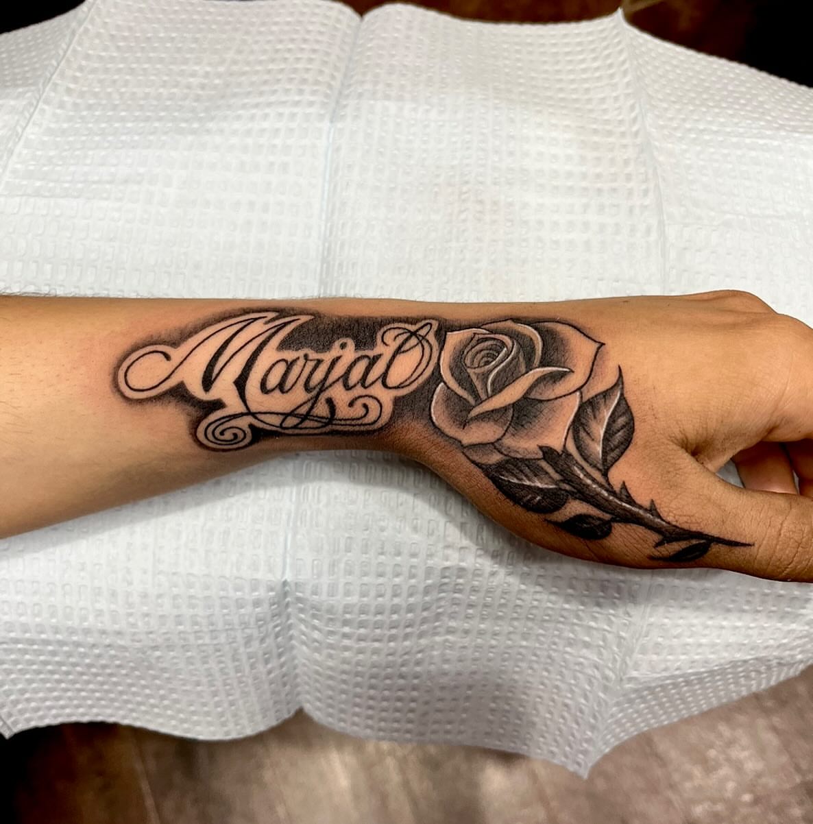 Rose and name black and grey tattoo on the forearm by Kenny Buck