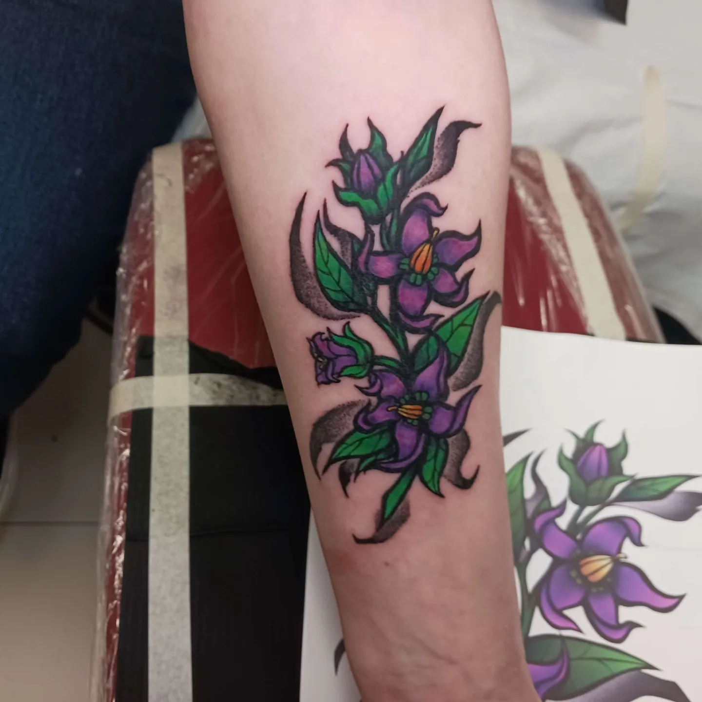 Purple flowers American traditional tattoo on the forearm by Chaz Escobar