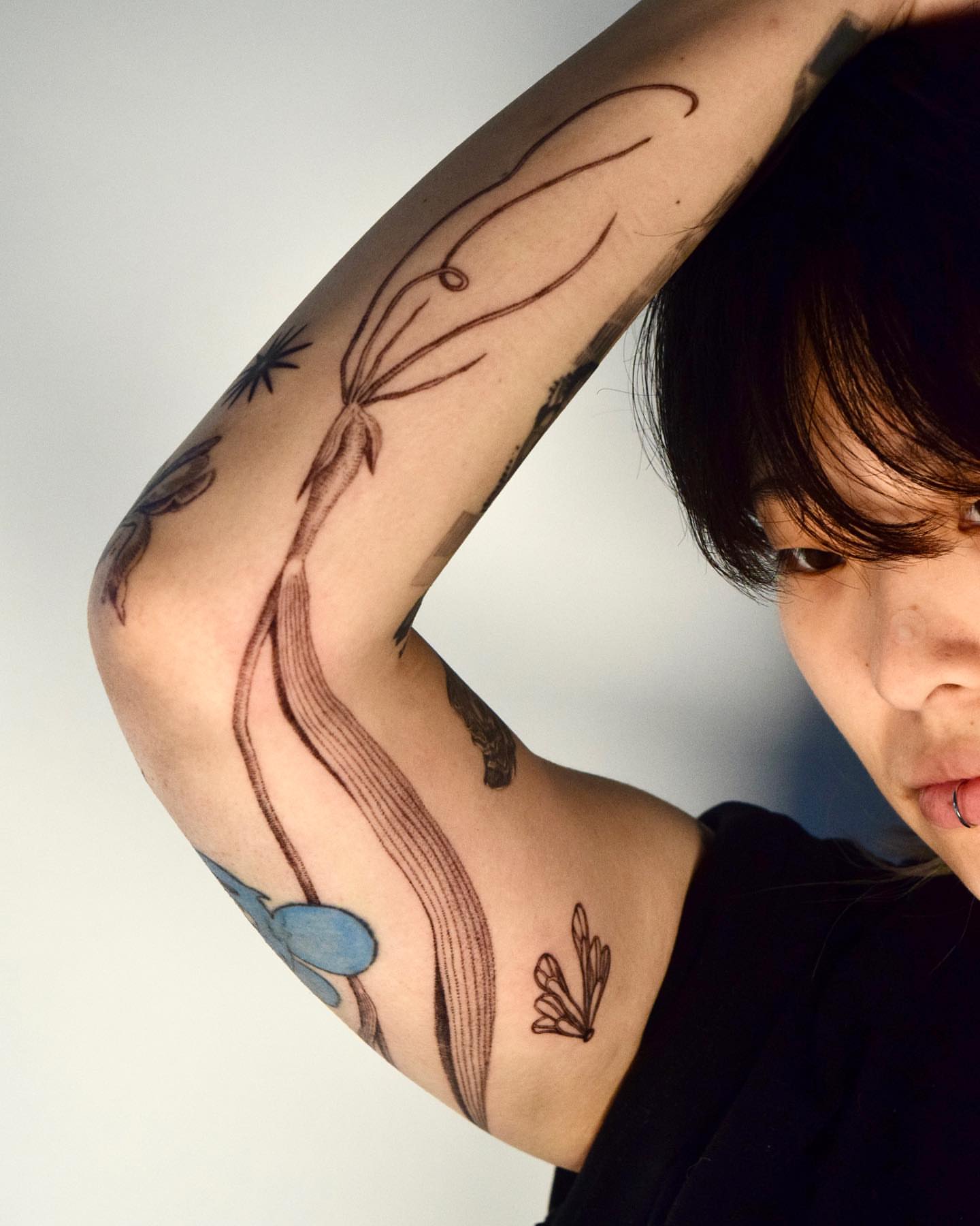 Abstract floral black and grey tattoo on the forearm by Stella Oh