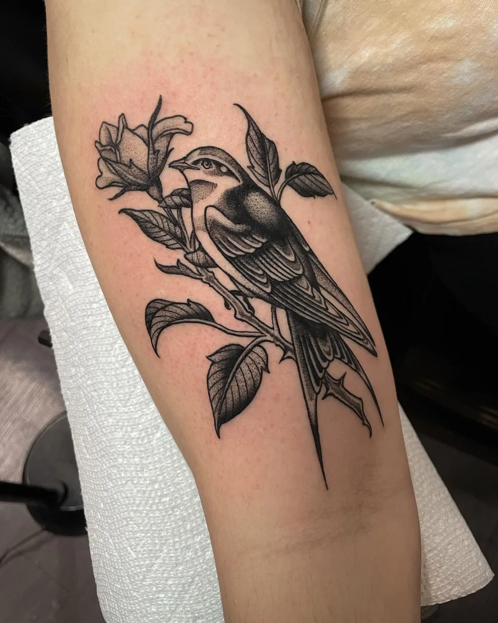 Bird and flower black and grey tattoo on the forearm by Lauren Vandevier