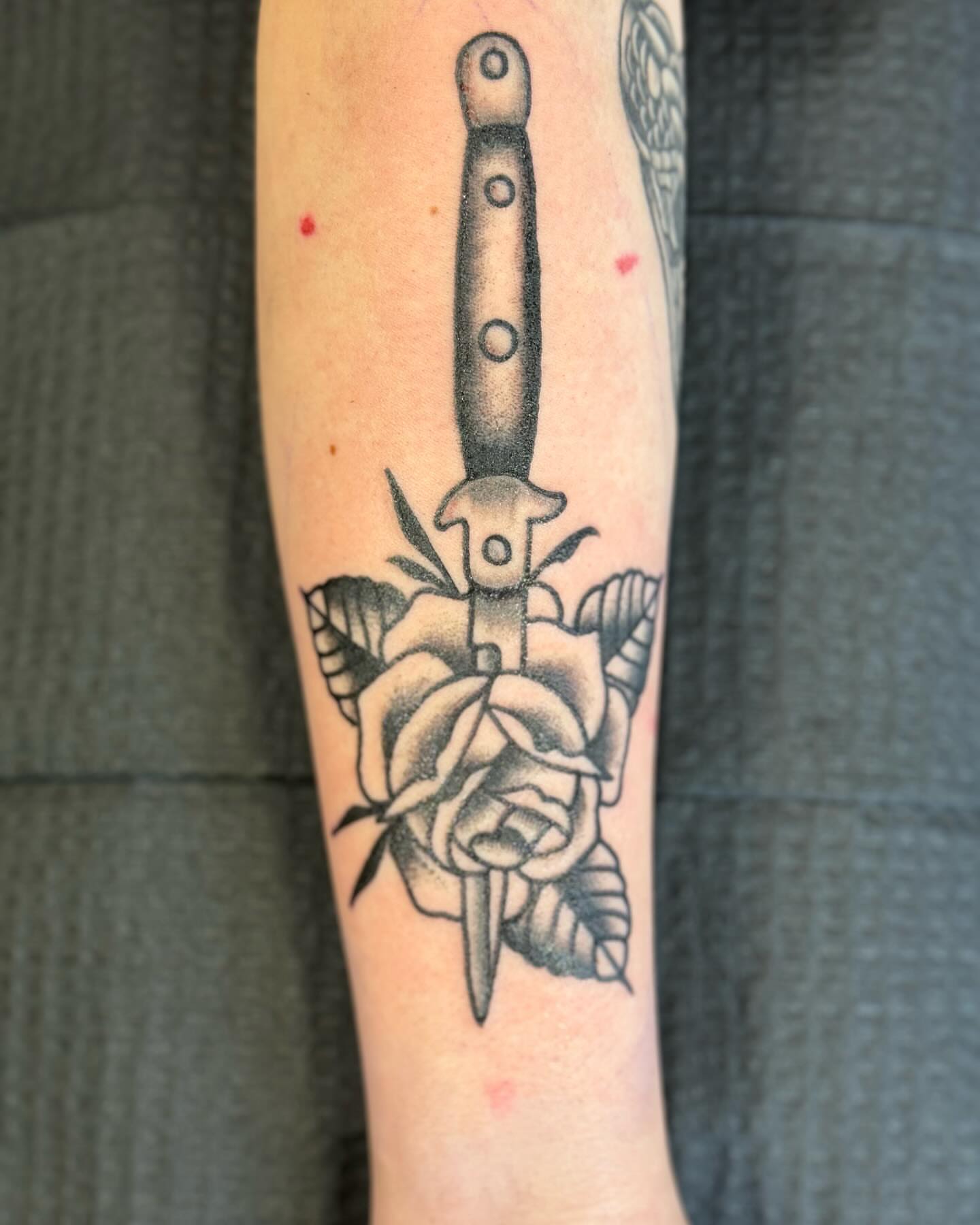 Knife and rose black and grey tattoo on the forearm by Minneapolis