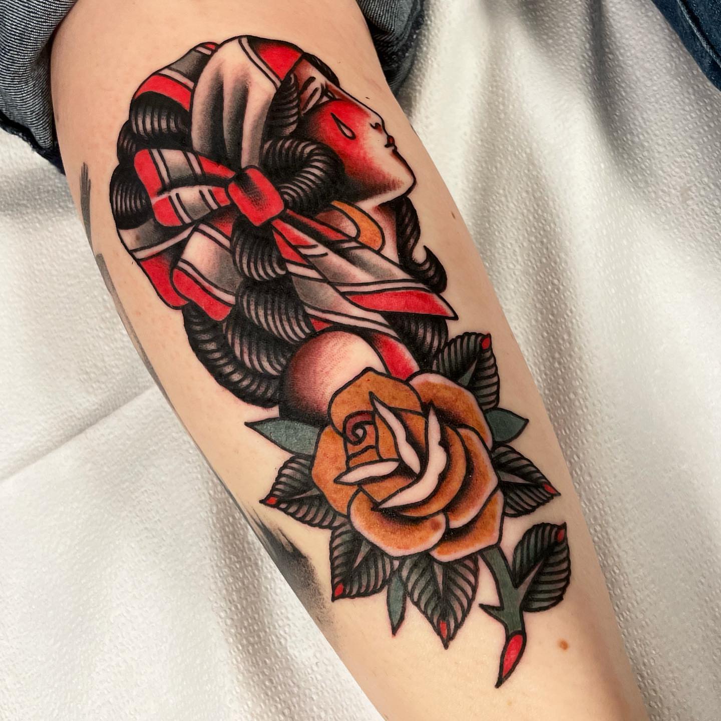 Geisha with rose American traditional tattoo on the forearm by Mike Hudgins