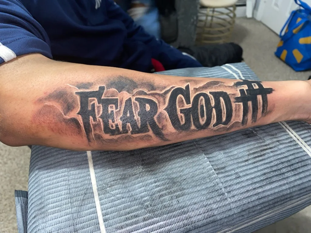 Fear god black and grey tattoo on the forearm by Daniel Illachek