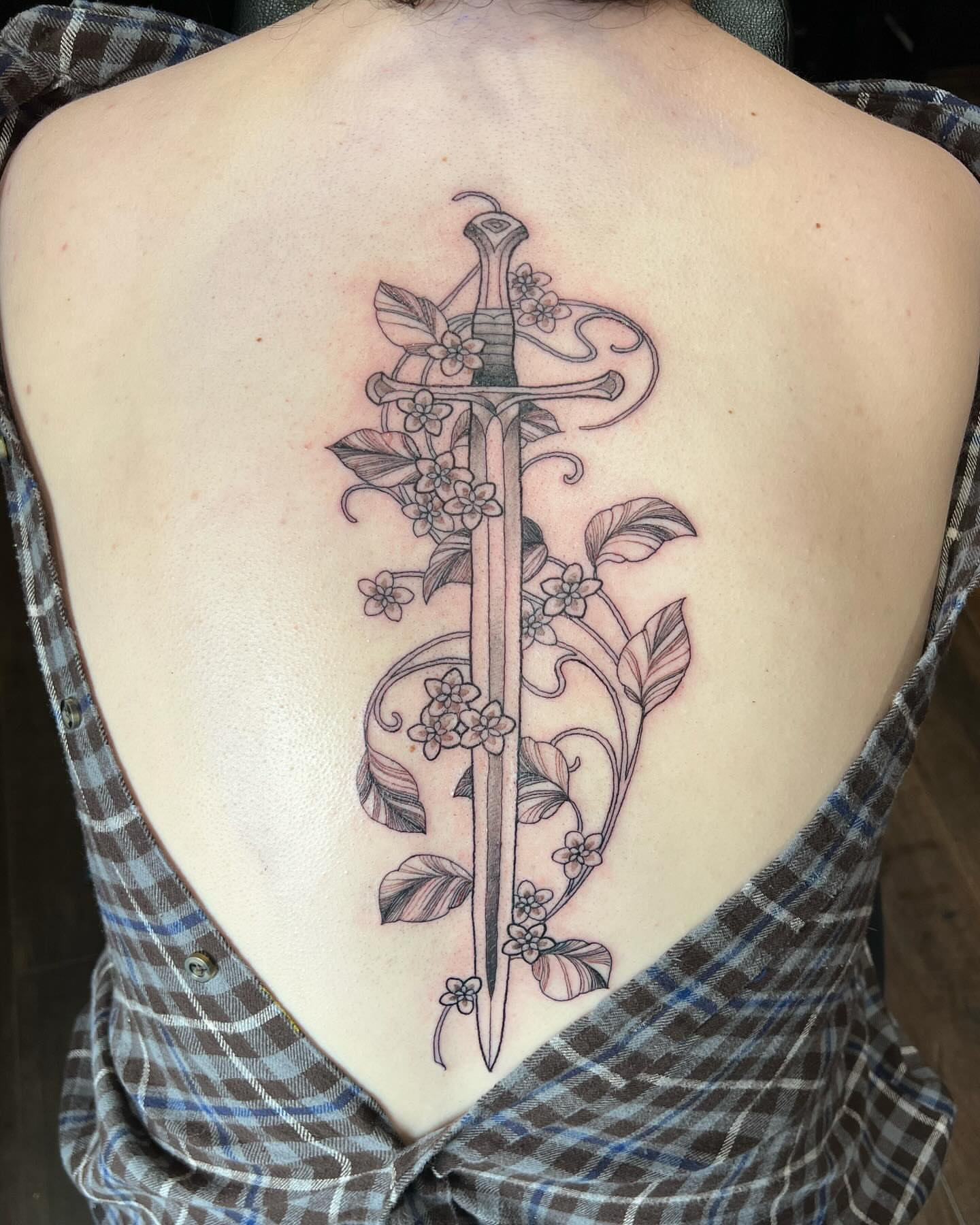 Sword and flowers black and grey tattoo on the back by Tattoos by Alli Wilcox