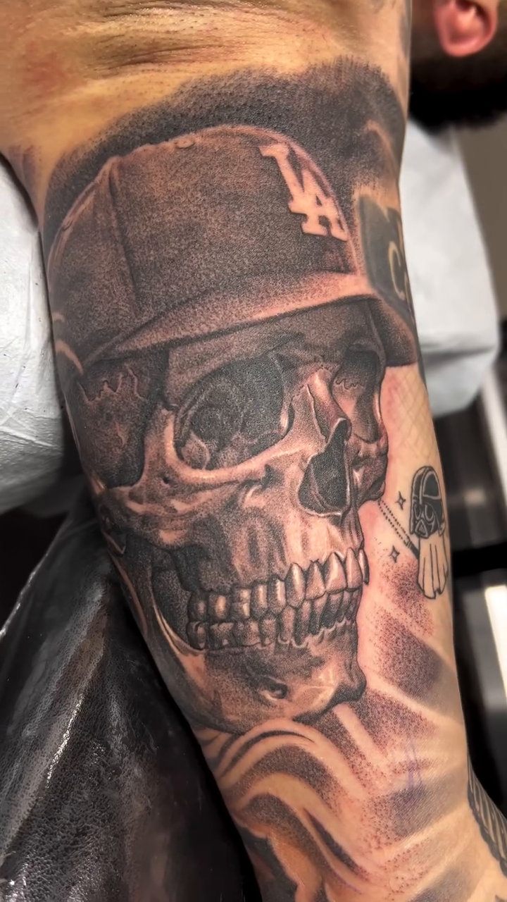 Skull wearing a baseball cap realism tattoo by Brian Hernandez