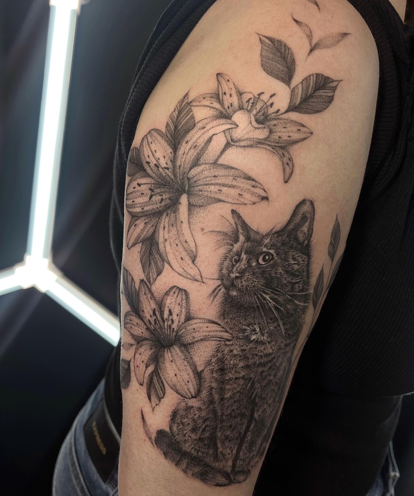 Cat and lilies realism tattoo on the upper arm by Tattoo Yulia Kononenko