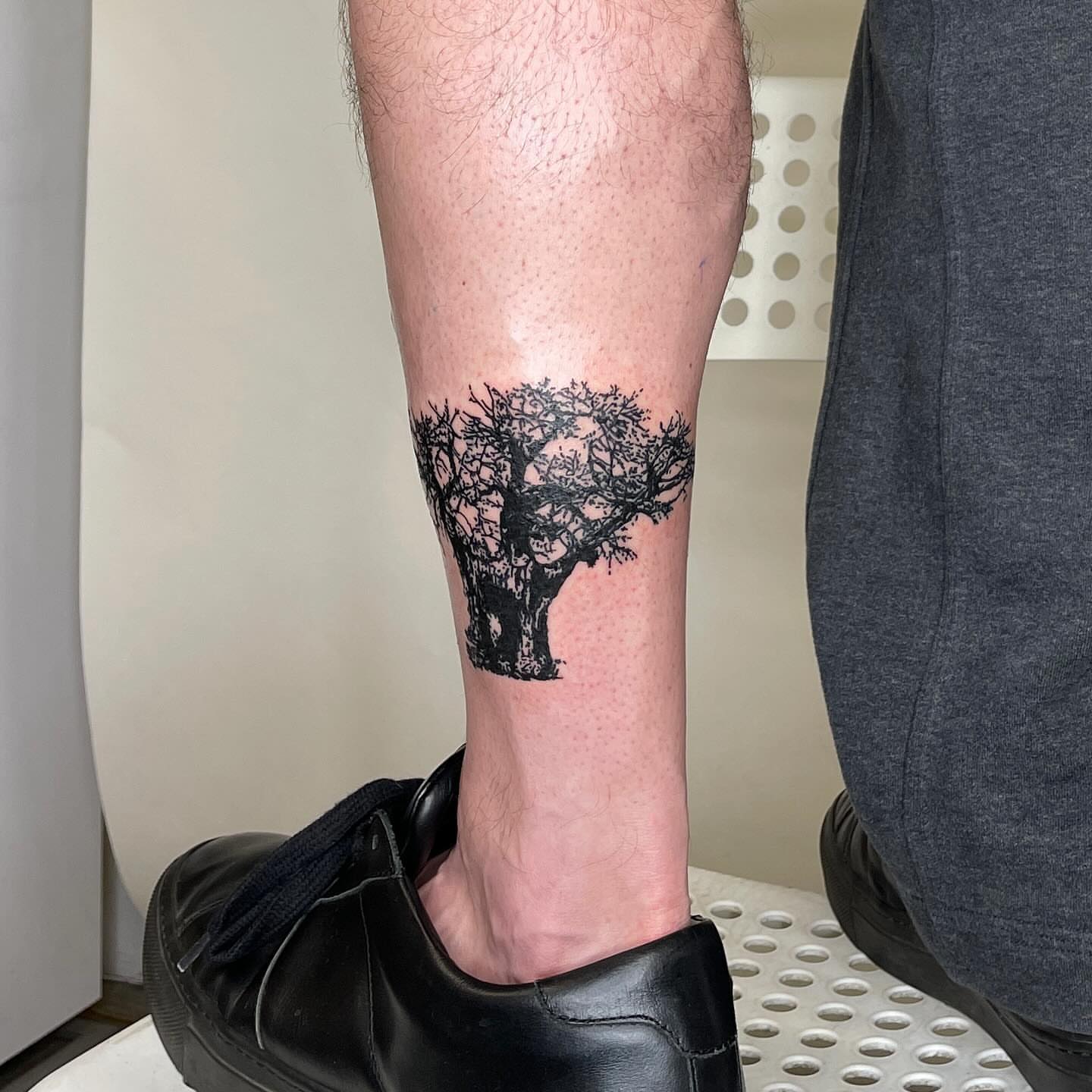 Tree black and grey tattoo on the calf by utility pole