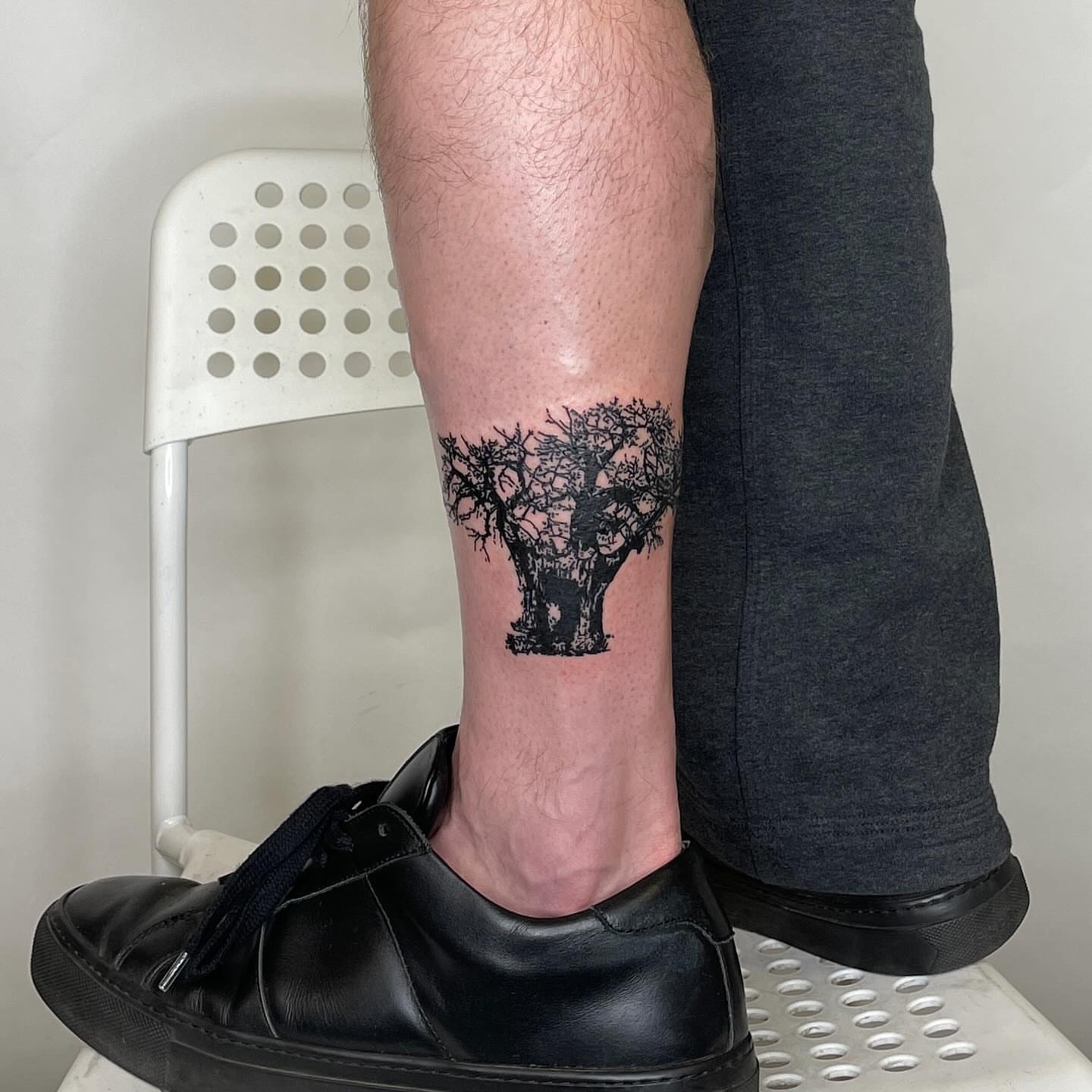 Tree black and grey tattoo on the calf by utility pole