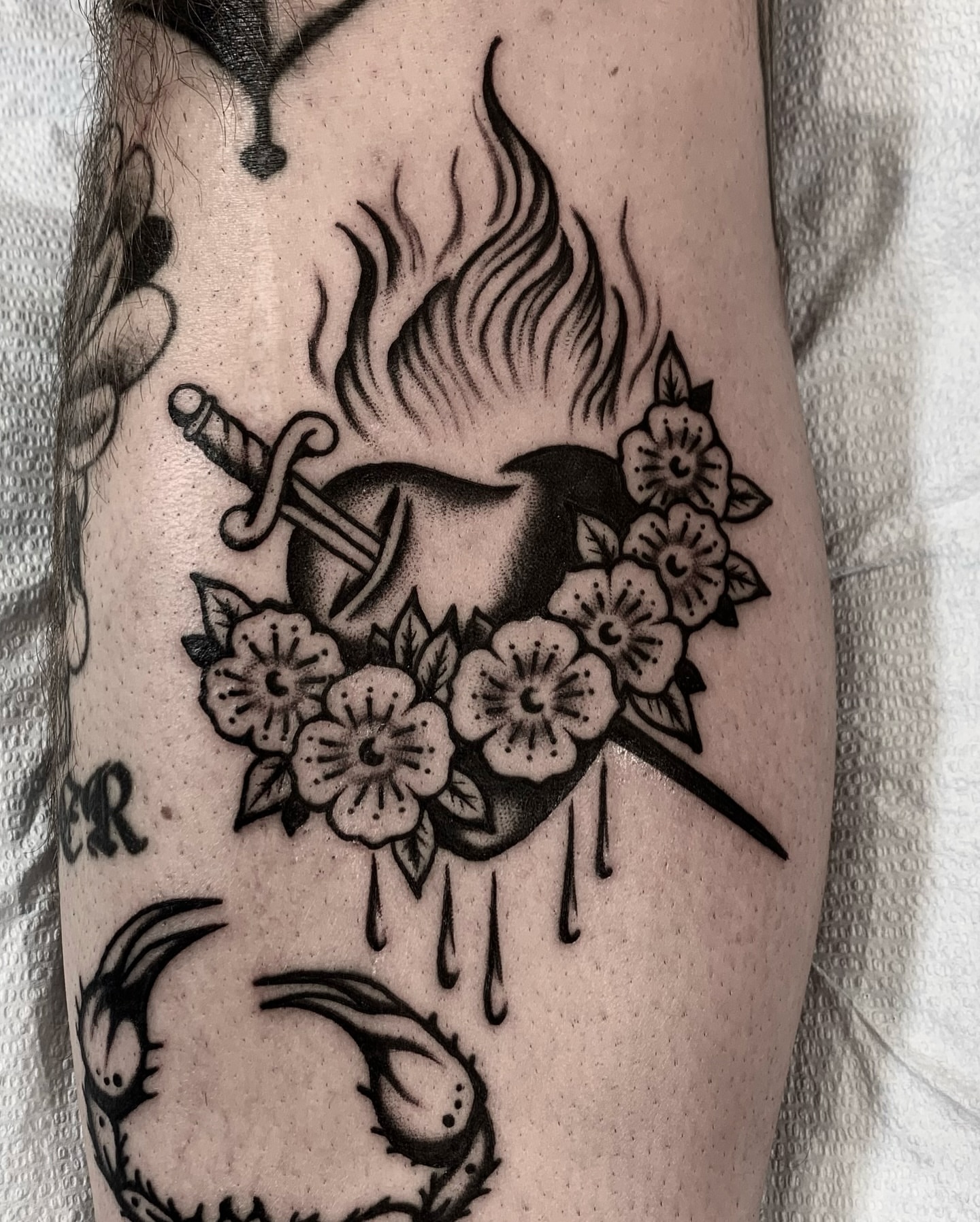 Heart with sword and flowers dotwork tattoo on the forearm by Weston Imhoff