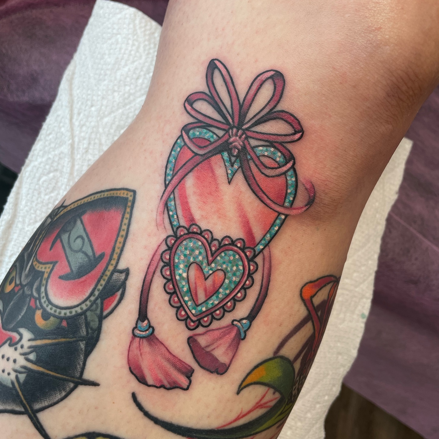 Heart-shaped gift box new school tattoo on the forearm by Angel, Salt Lake City, Utah