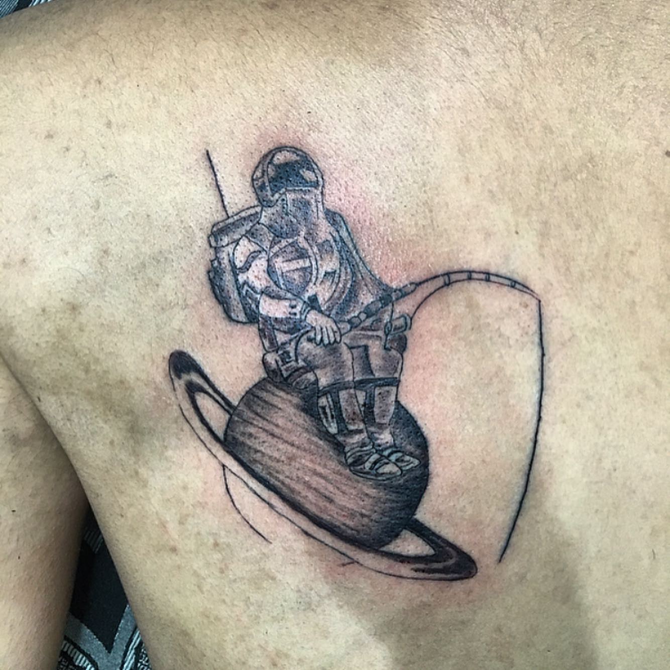 Astronaut on planet black and grey tattoo on the back by la flamme