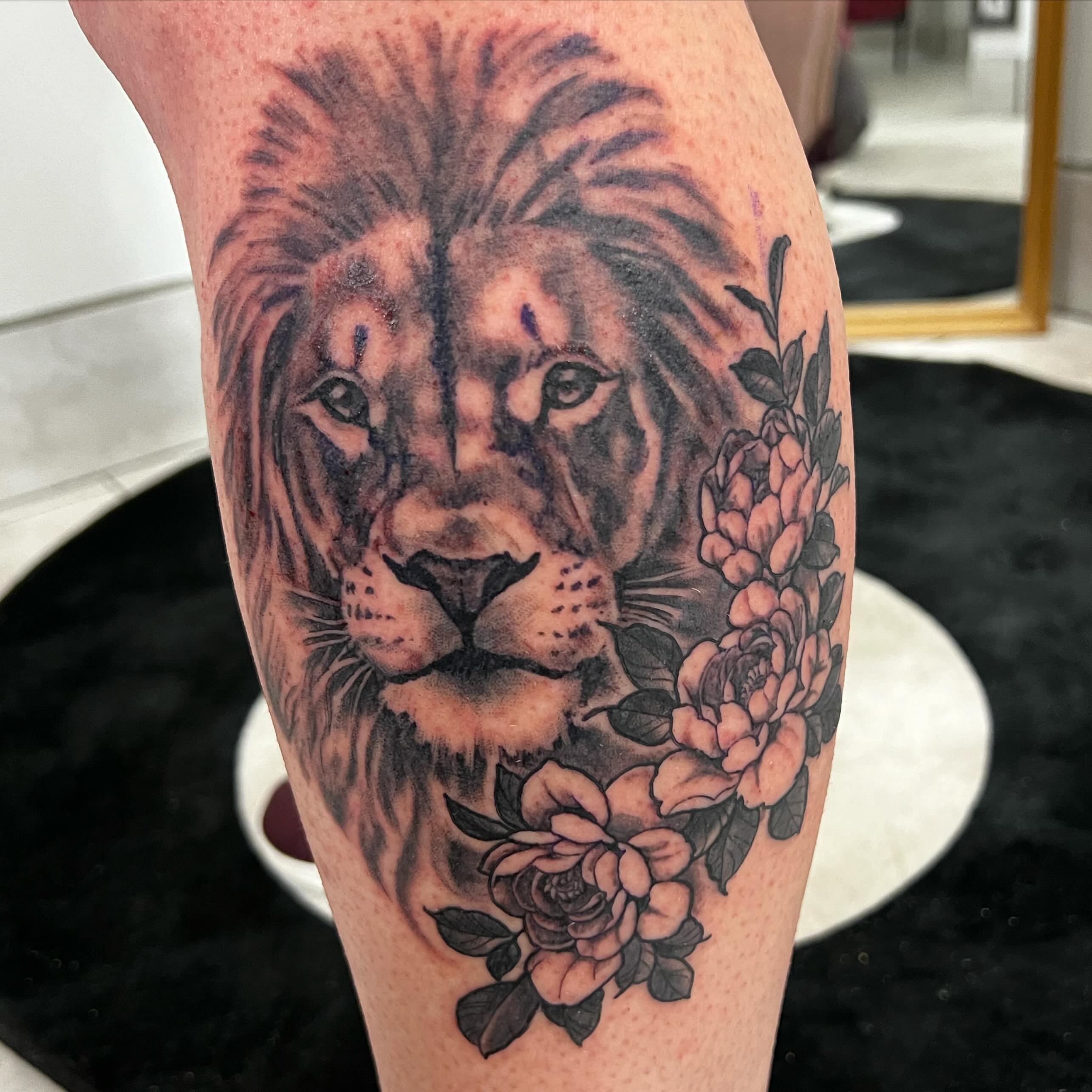 Lion with flowers realism tattoo on the forearm by Levi Cox, Powell, Ohio