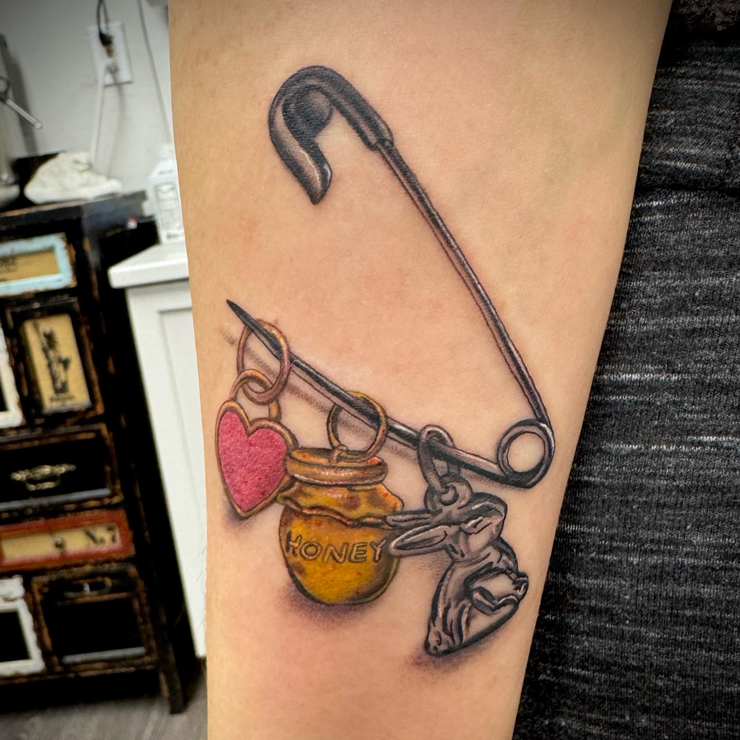Safety pin and honey jar black and grey tattoo on the forearm by MR