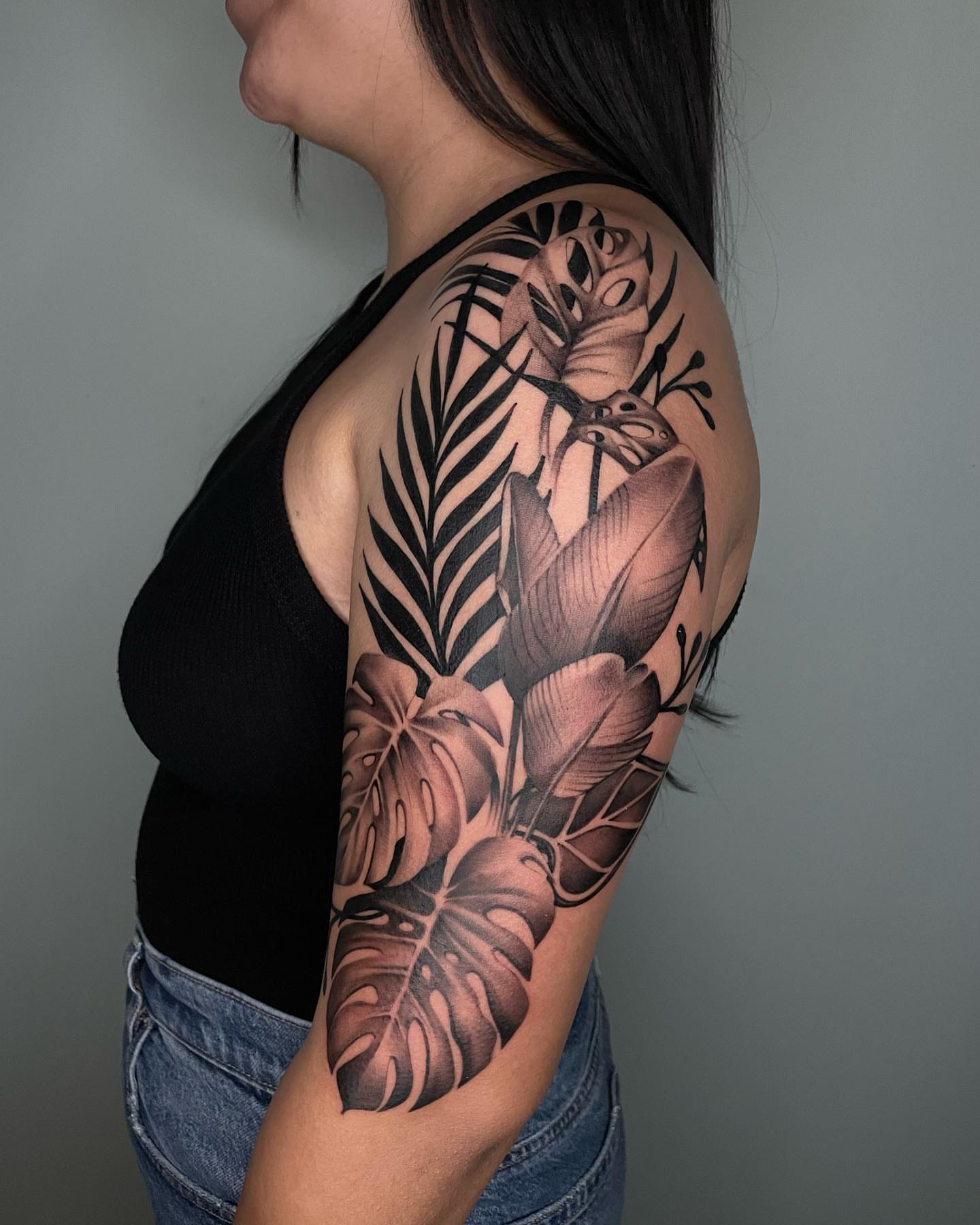 Tropical leaves black and grey tattoo on the upper arm by Angel, Salt Lake City, Utah