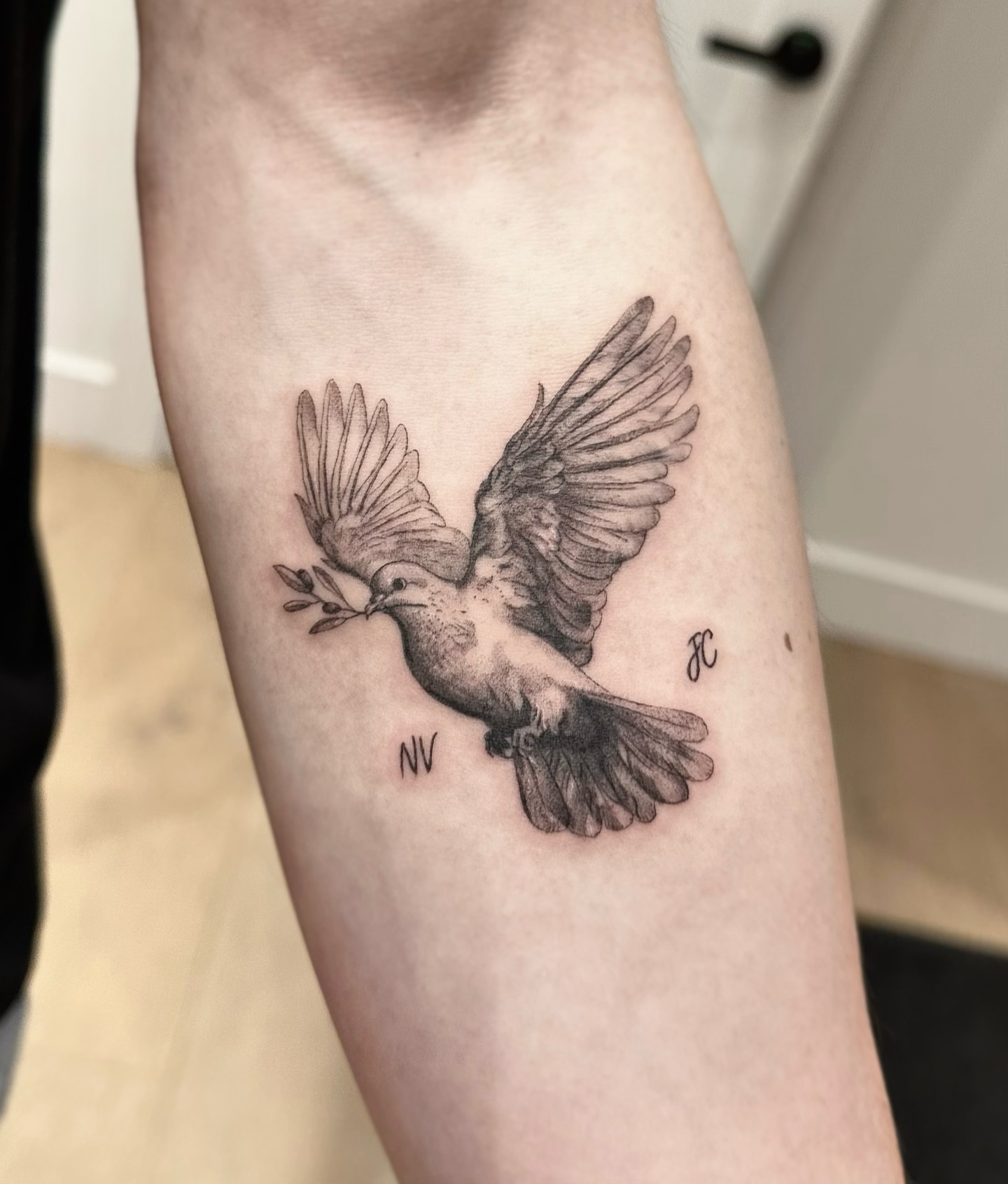 Bird with branch black and grey tattoo on the forearm by Oxana