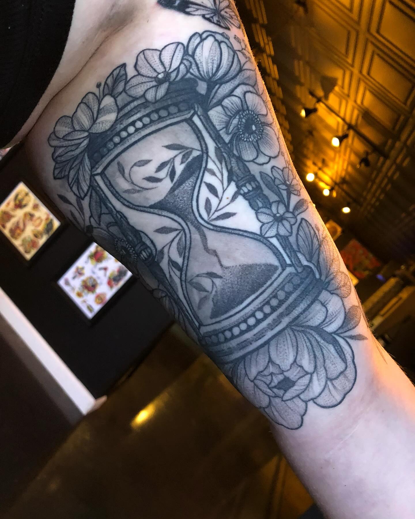 Hourglass with floral wreath black and grey tattoo on the forearm by Melissa Brown