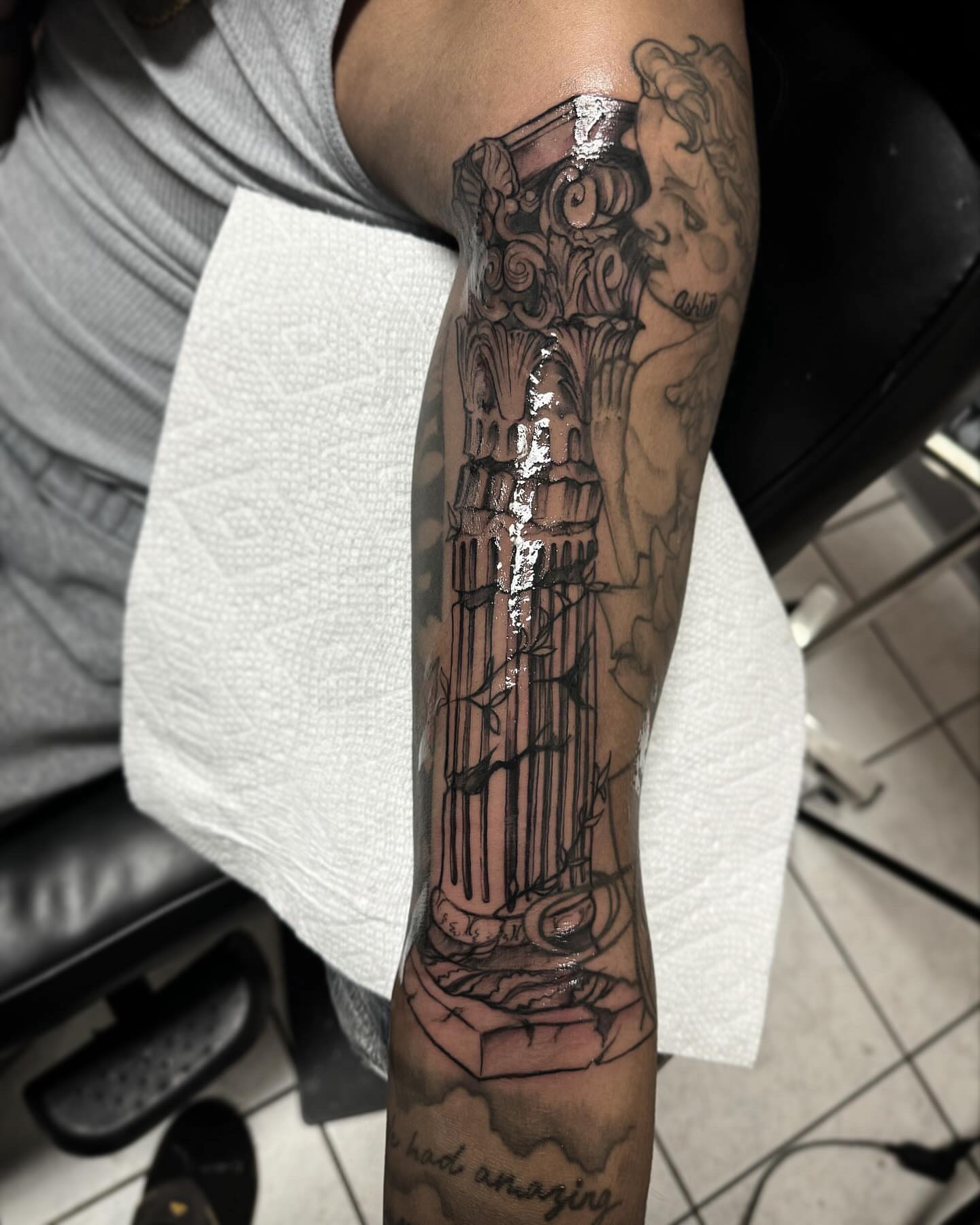 Column with cherub black and grey tattoo on the forearm by @inkhazmat