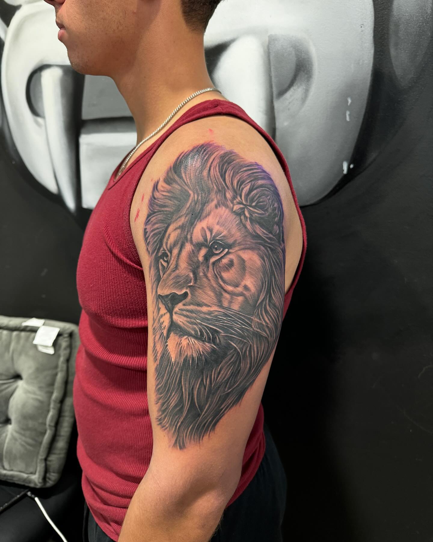 Lion realism tattoo on the upper arm by Tattoos By Chico