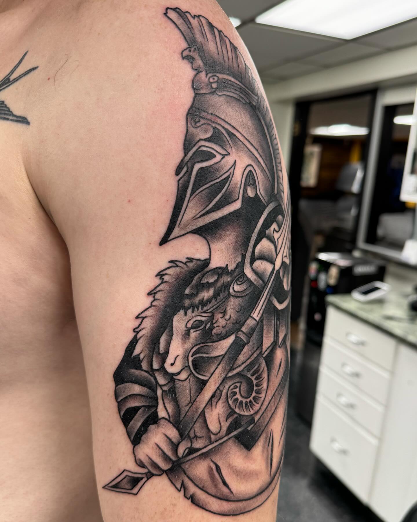 Goat and warrior black and grey tattoo on the shoulder by Cory Perry-Servellon