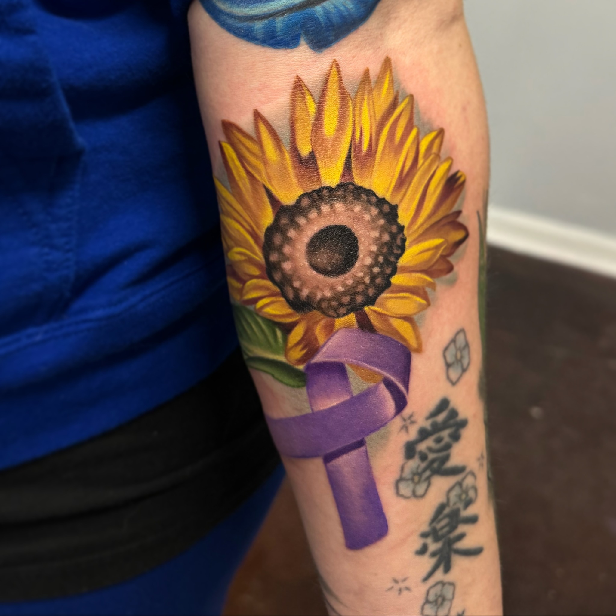 Sunflower and purple ribbon realism tattoo on the forearm by Kyle hodge