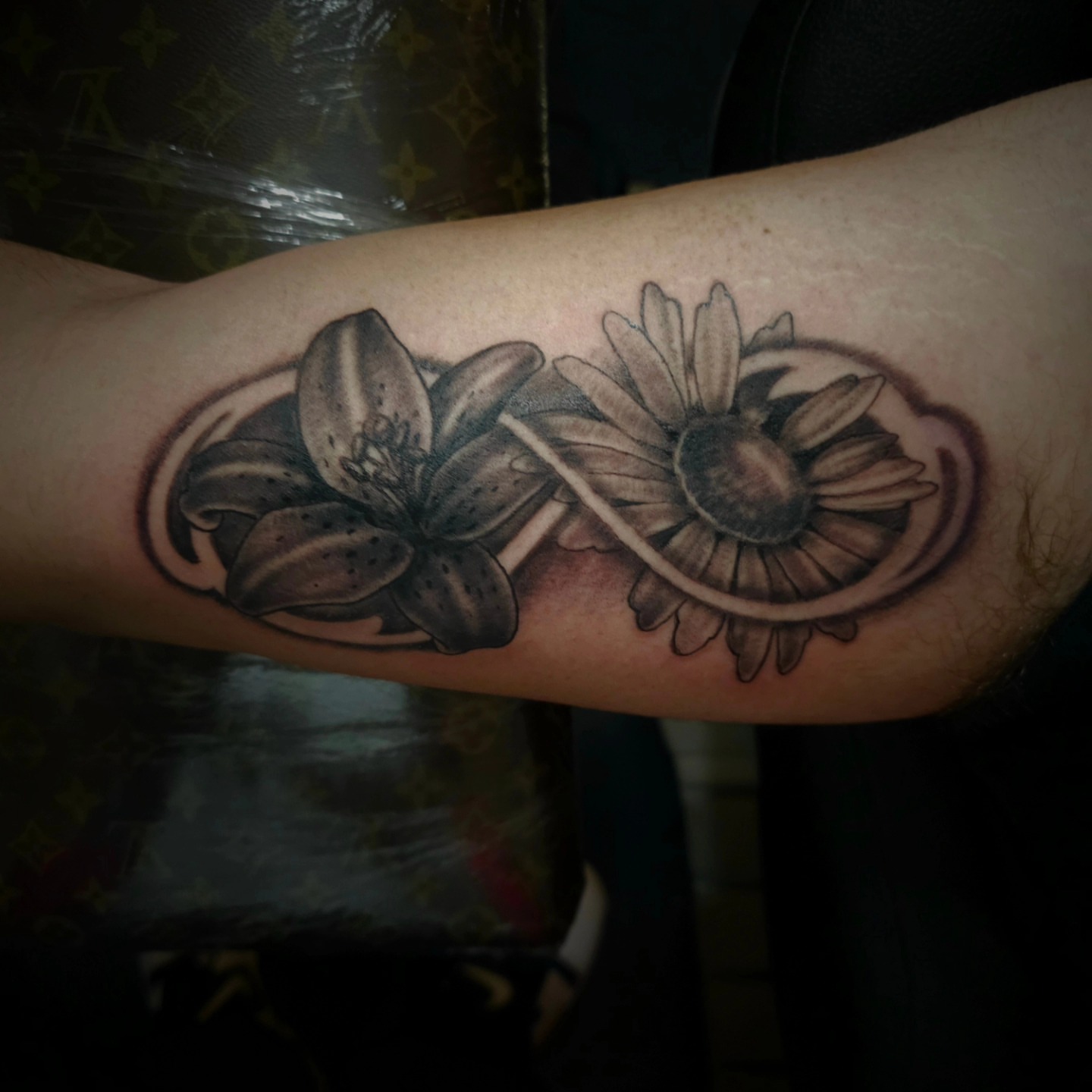 Lily and daisy black and grey tattoo on the forearm by Germaine Sherman