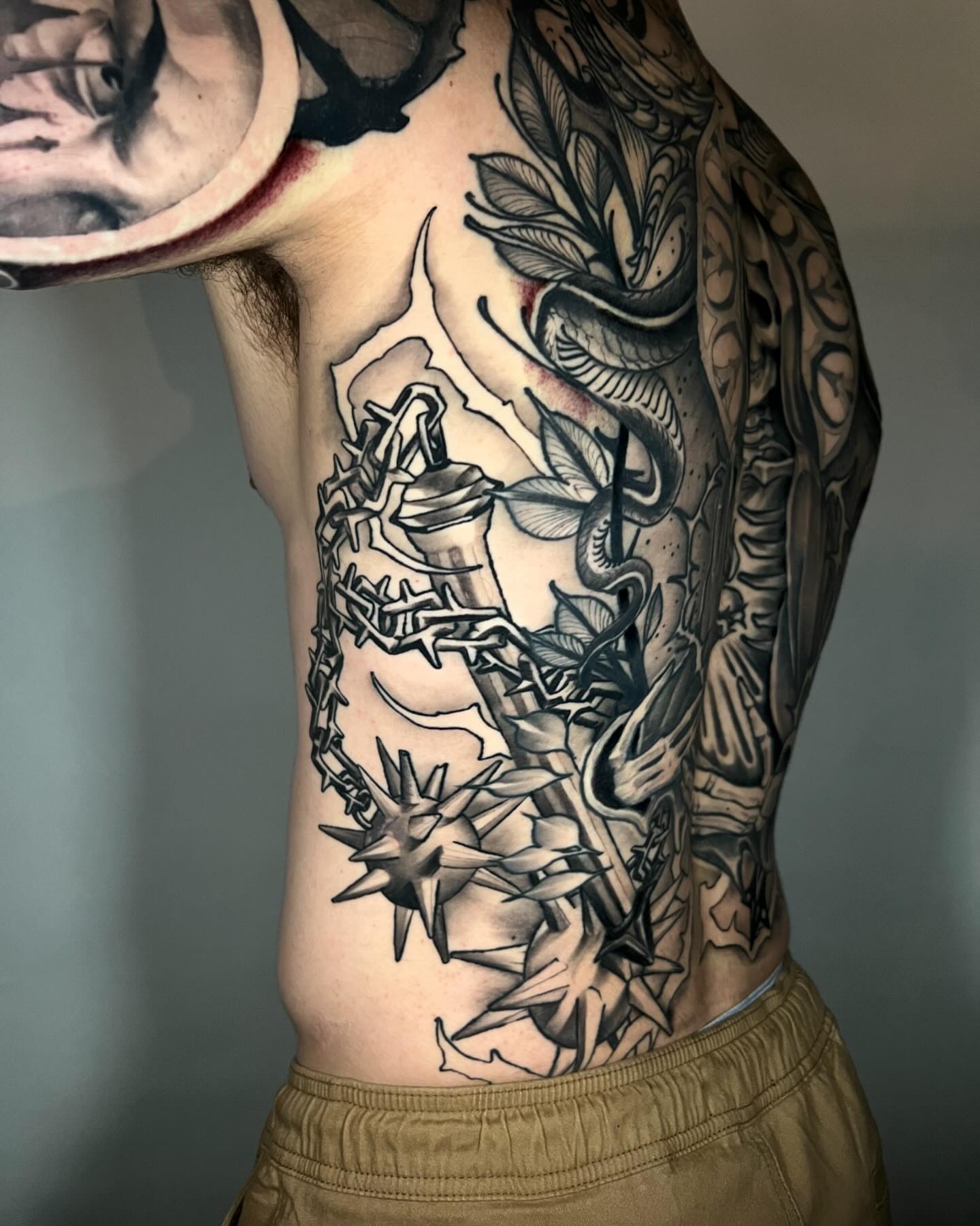 Barbed wire and flowers geometric tattoo on the ribs by Joshua Weeks