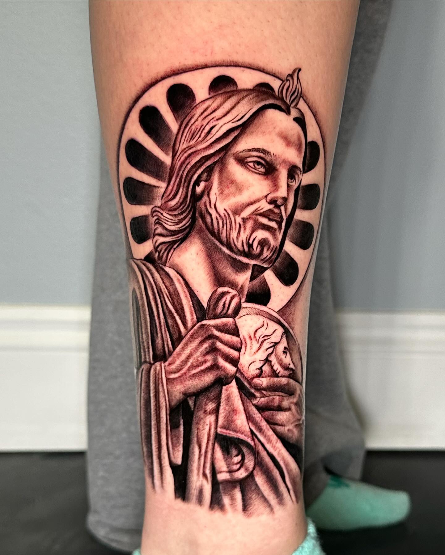 Religious figure holding child realism tattoo on the forearm by Christopher Heffley