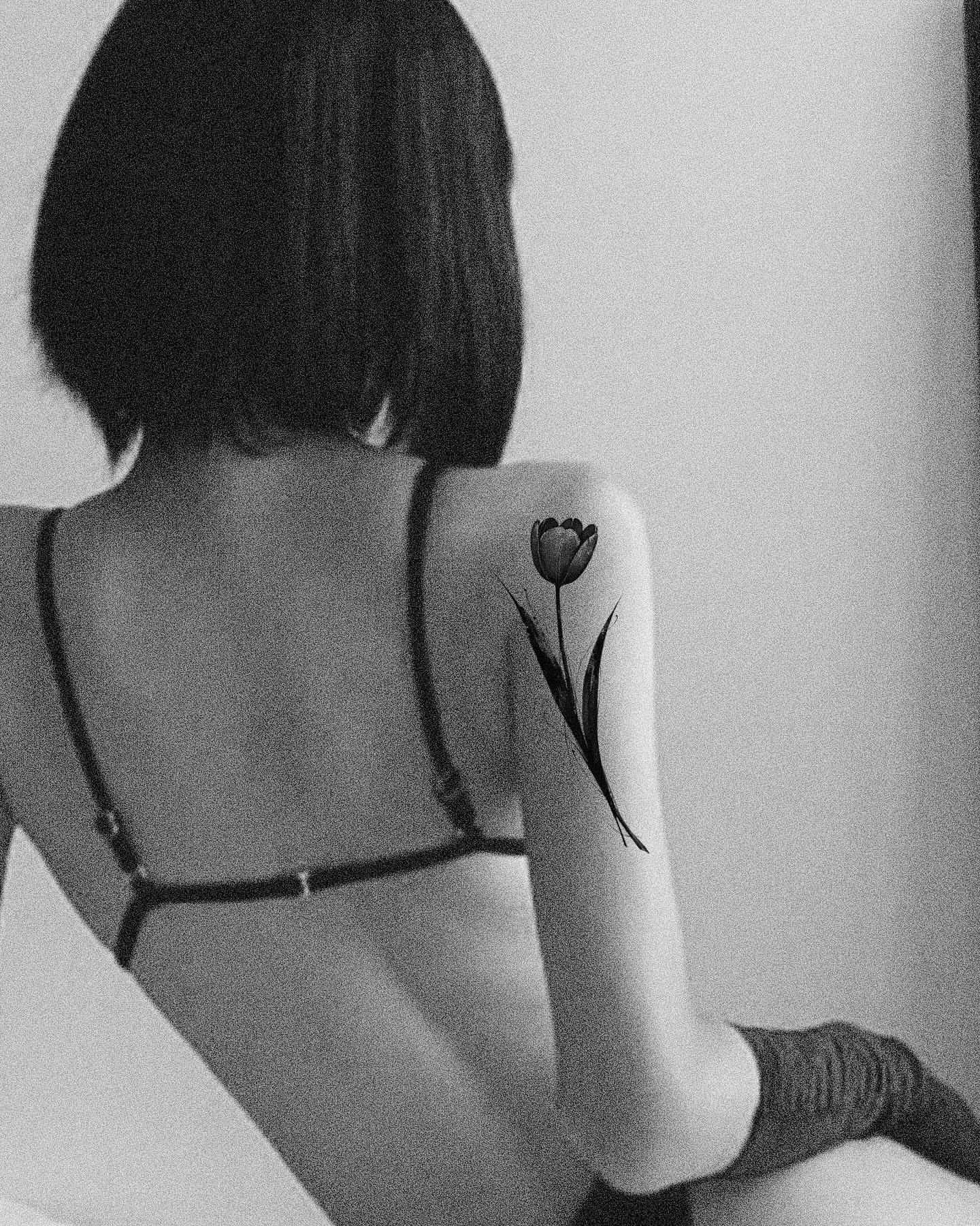 Tulip black and grey tattoo on the upper arm by 𝑴𝒆𝒍𝒐