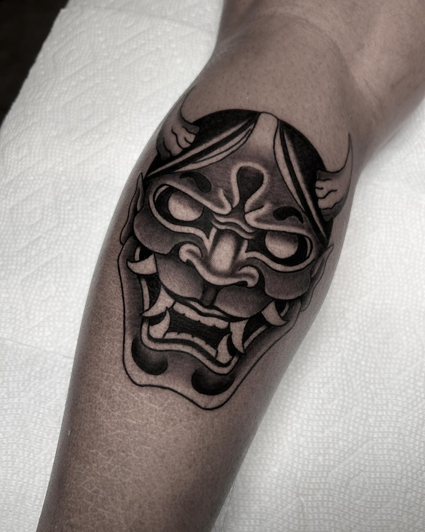 Demon mask black and grey tattoo on the forearm by Mitch Hoggard