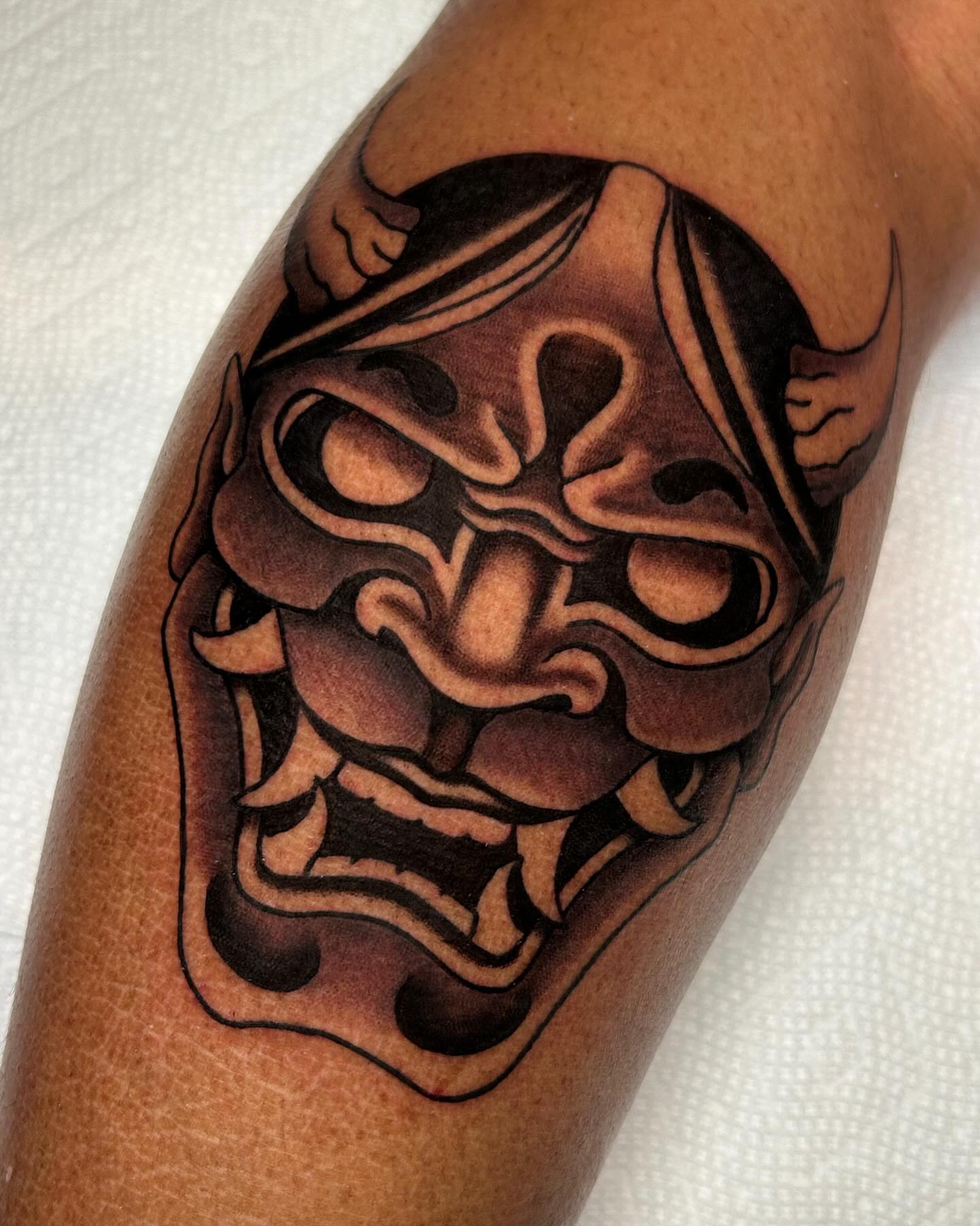 Demon mask black and grey tattoo on the forearm by Mitch Hoggard