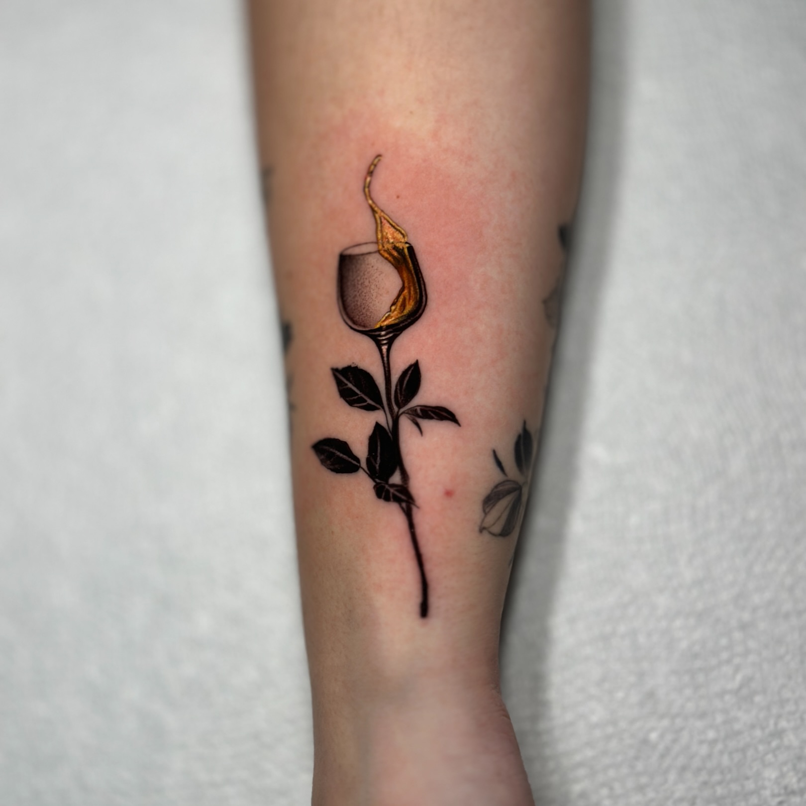 Burning wine glass realism tattoo on the forearm by Robert Morton, Cleveland, Ohio