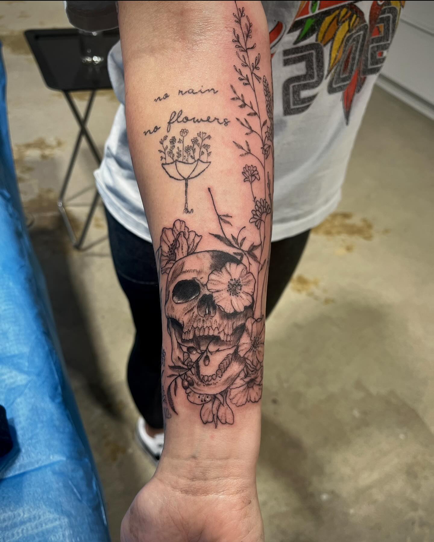 Skull with flowers realism tattoo on the forearm by Deville Pinson