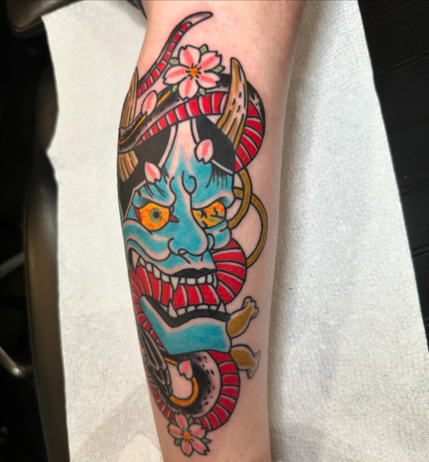 Mask with horns American traditional tattoo on the forearm by 𝕯𝖗𝖊𝖜 𝕲𝖎𝖑𝖊𝖘 𝕵𝖆𝖙𝖙𝖔𝖔, Addison, Texas
