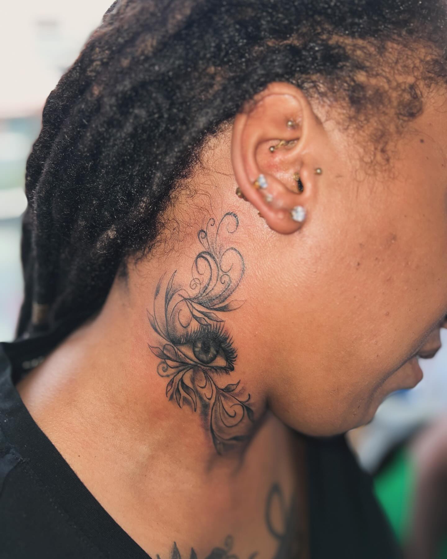 Eye with floral swirls black and grey tattoo on the neck by oxideTattoo, Morne-à-l'Eau