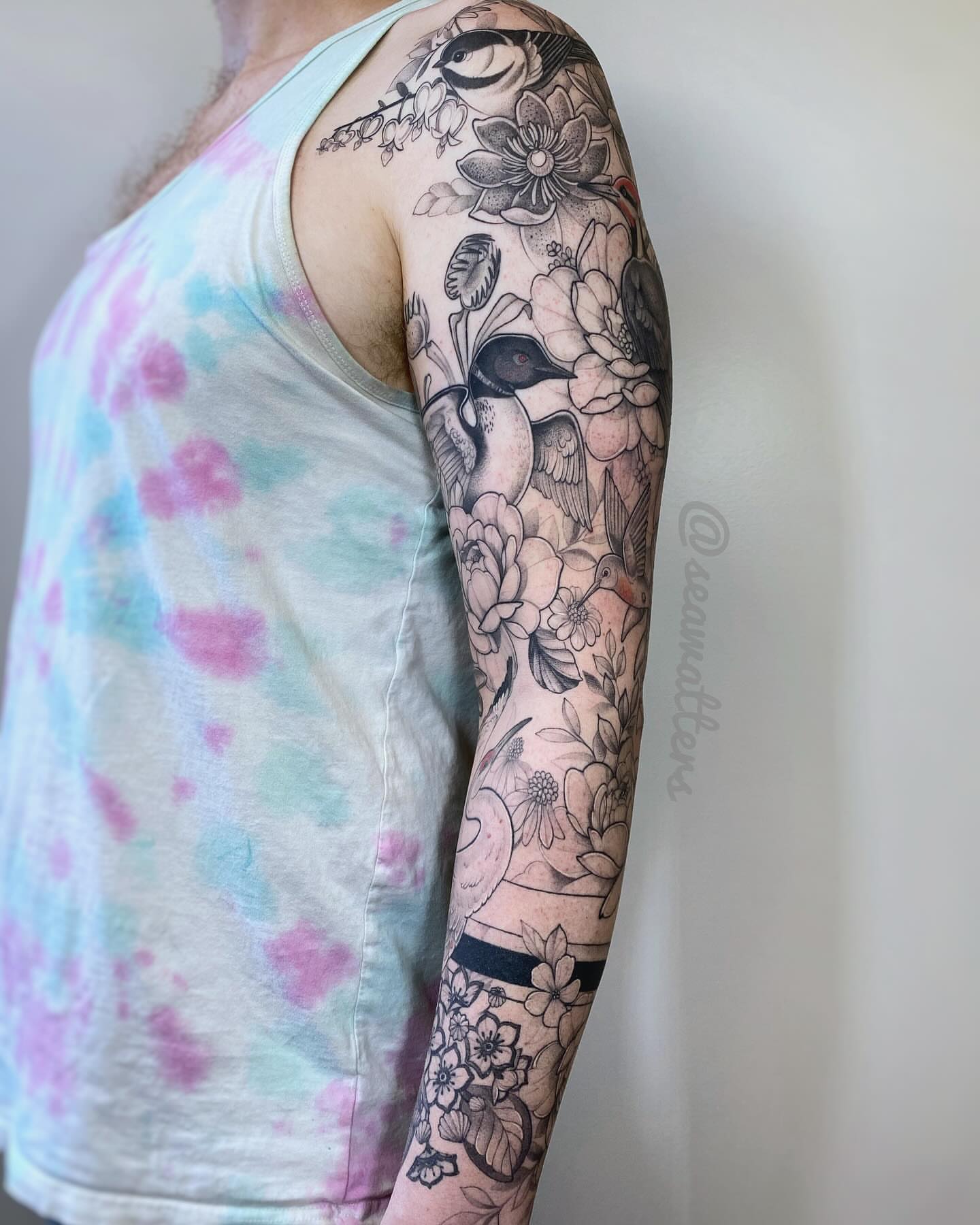 Floral and bird black and grey tattoo on the upper arm by Caitlin Watters