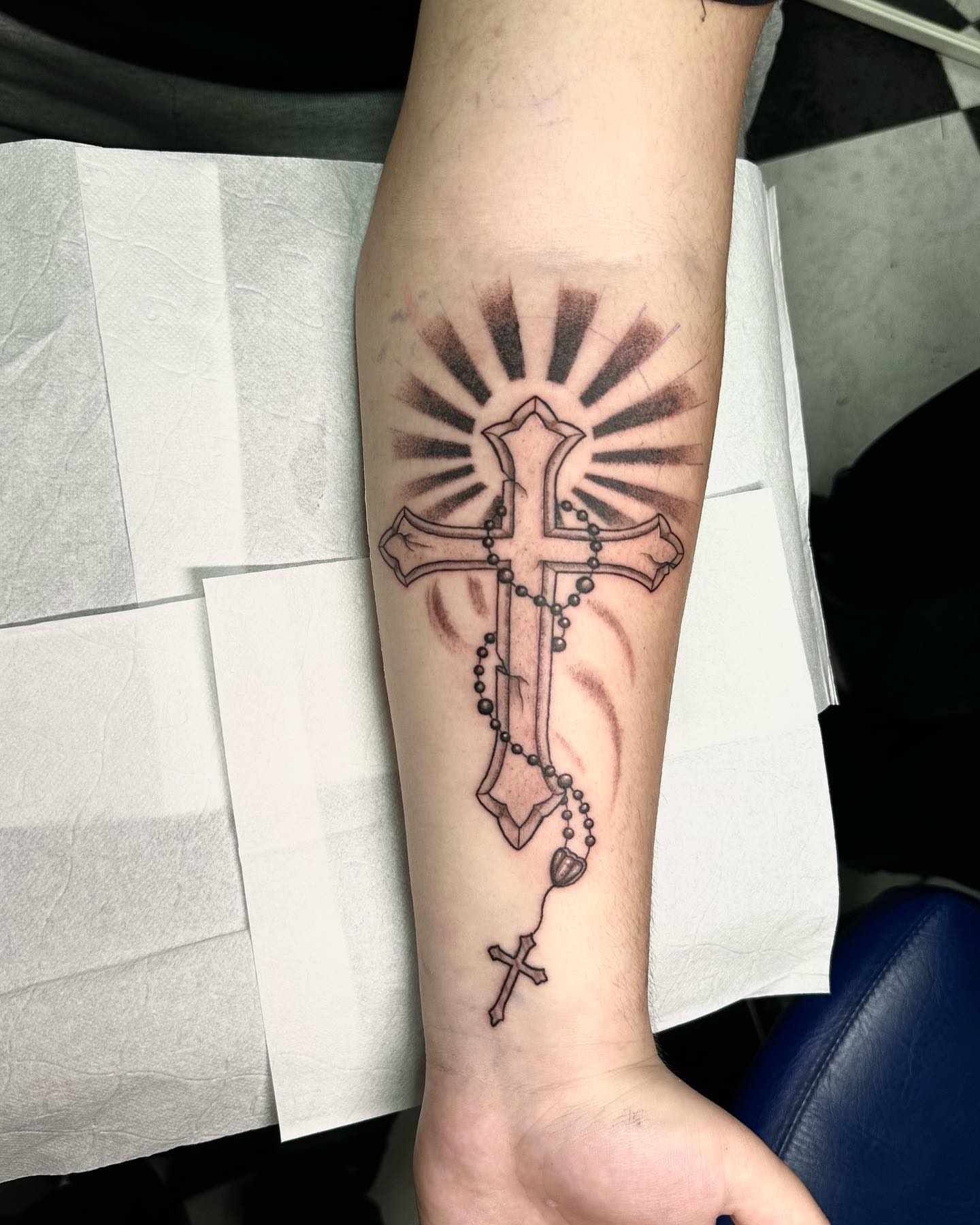 Cross with rosary black and grey tattoo on the forearm by Kunaytattoo