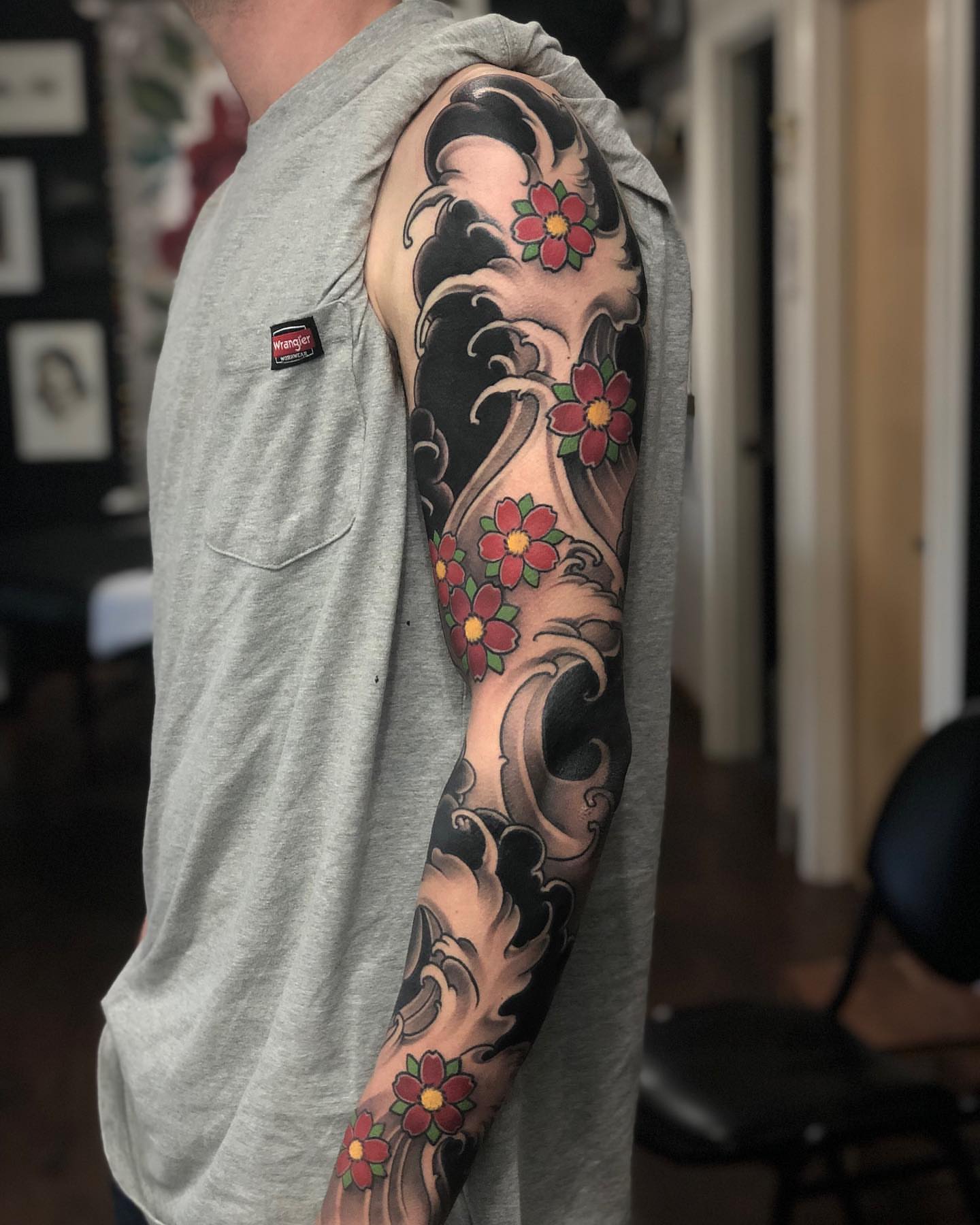 Wave and flowers japanese irezumi tattoo on the upper arm by Aaron Borden