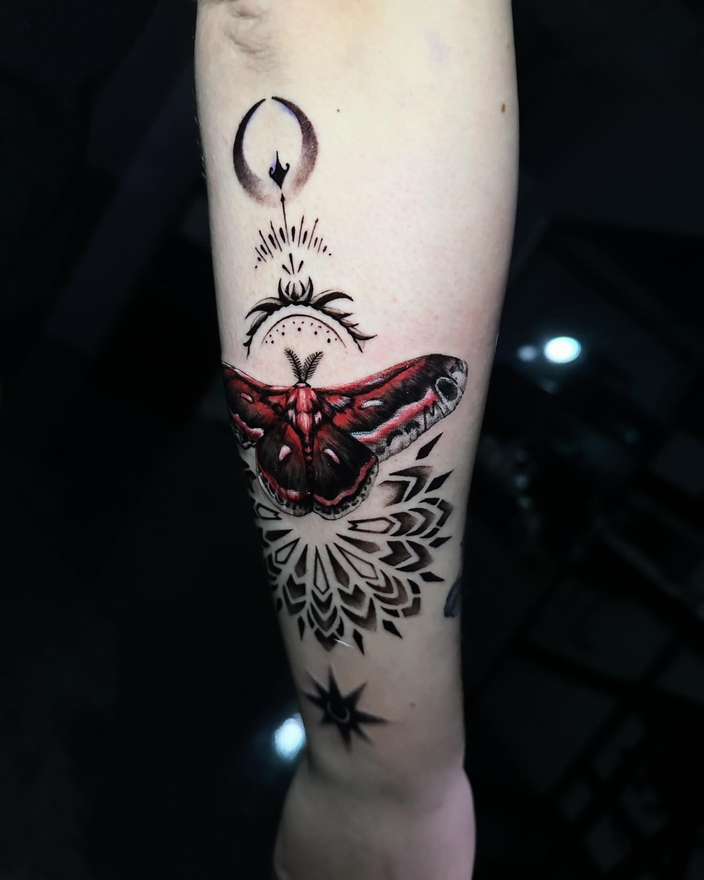 Moth and celestial symbols geometric tattoo on the forearm by Angel Gonzalez