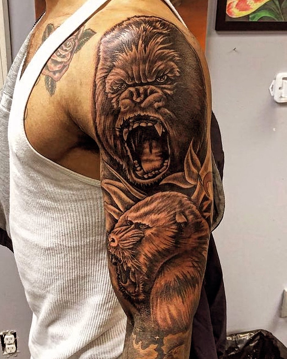 Gorilla and lion realism tattoo on the upper arm by Adrian Shan Carr