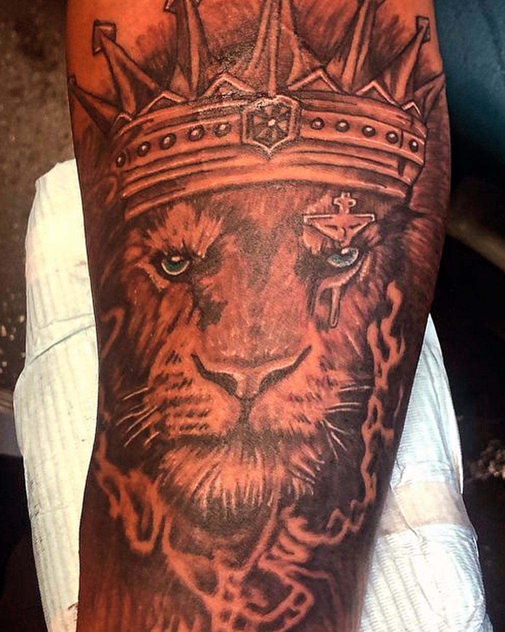 Lion with crown realism tattoo on the forearm by Adrian Shan Carr
