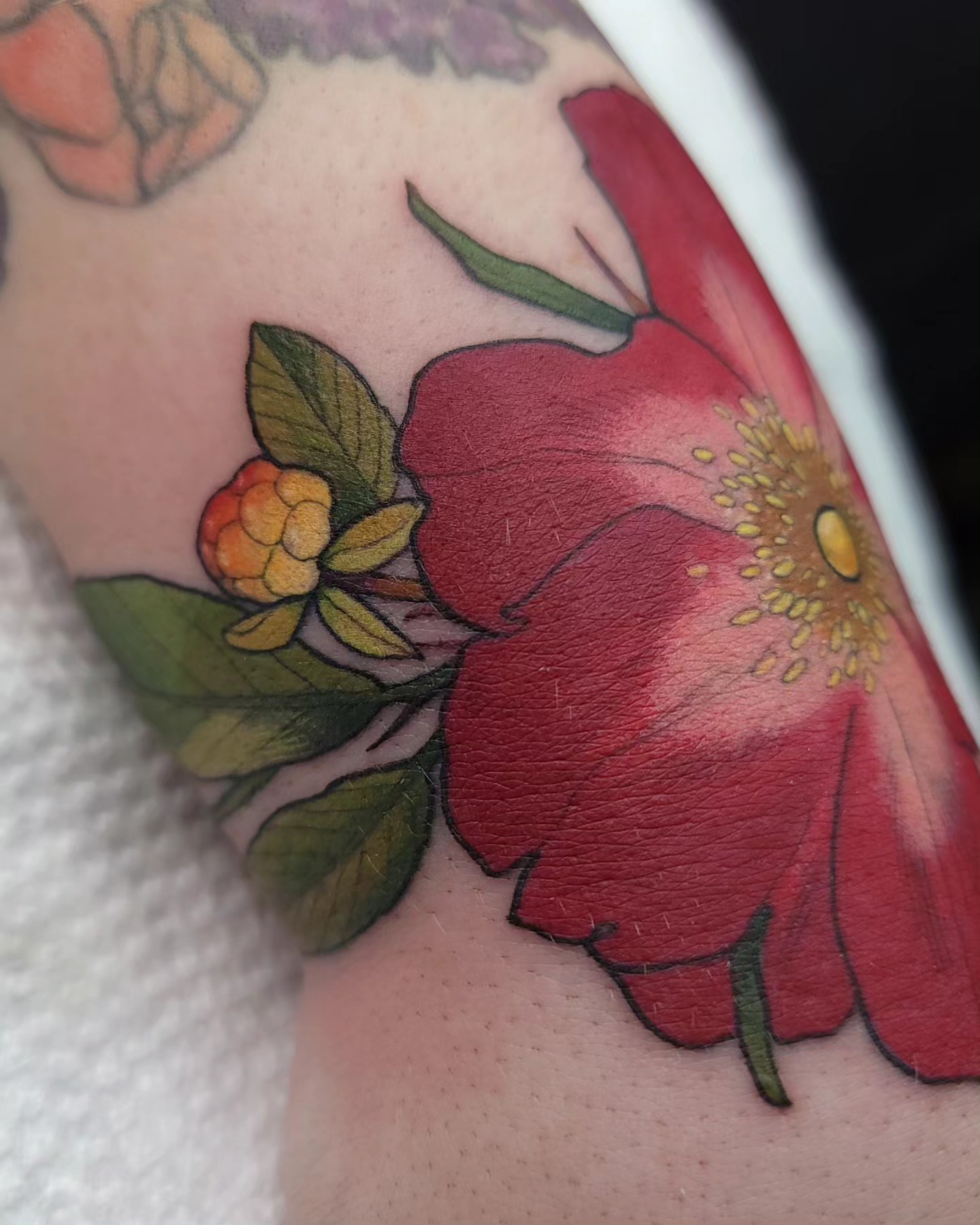 Red flower realism tattoo on the forearm by Ghost