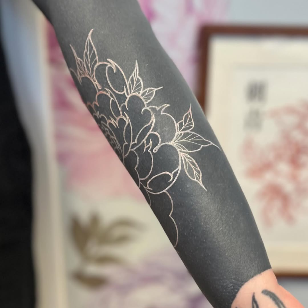 Flower outline on black background Japanese tattoo on the forearm by Garden Glow Tattoo