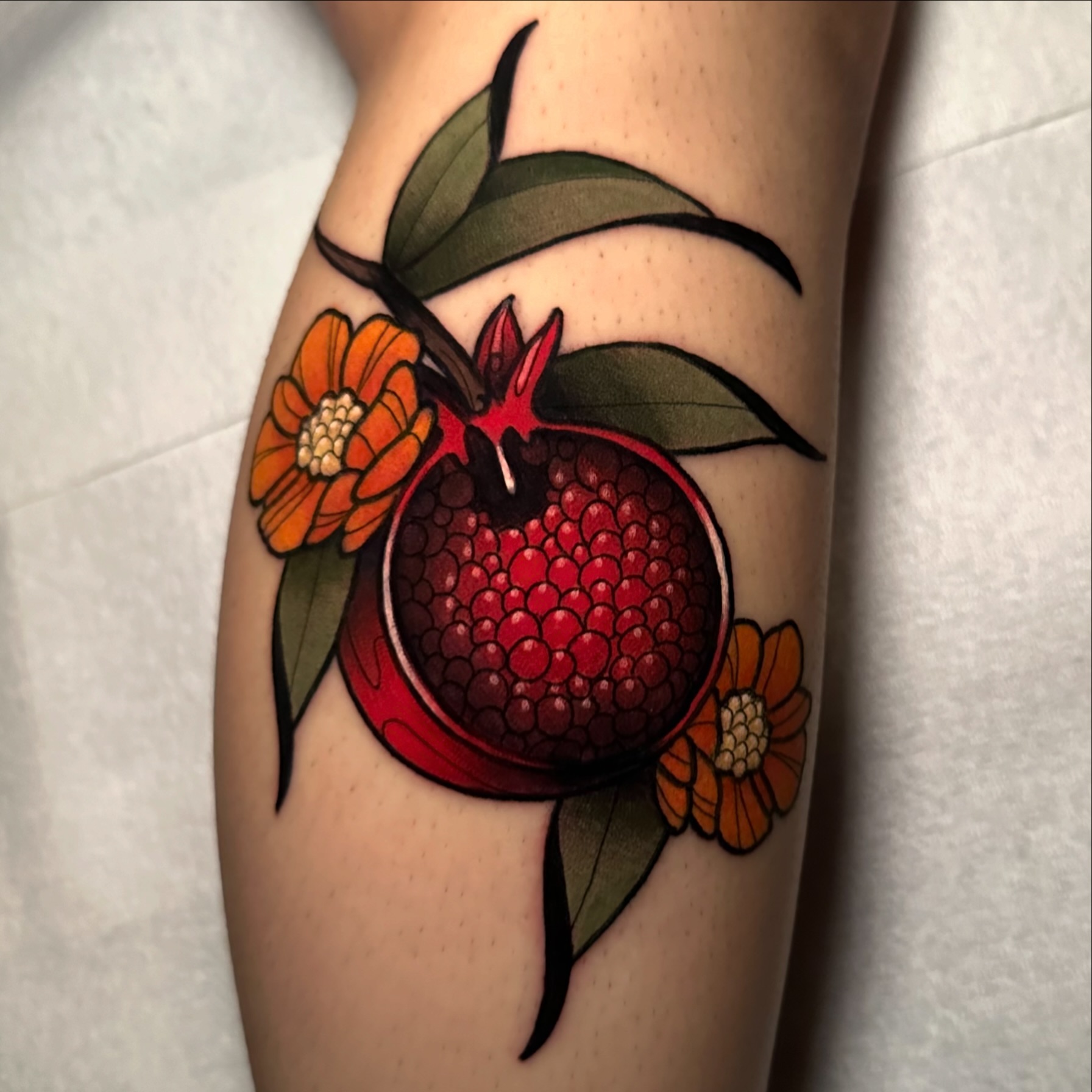 Pomegranate and flowers realism tattoo on the forearm by gillian marie