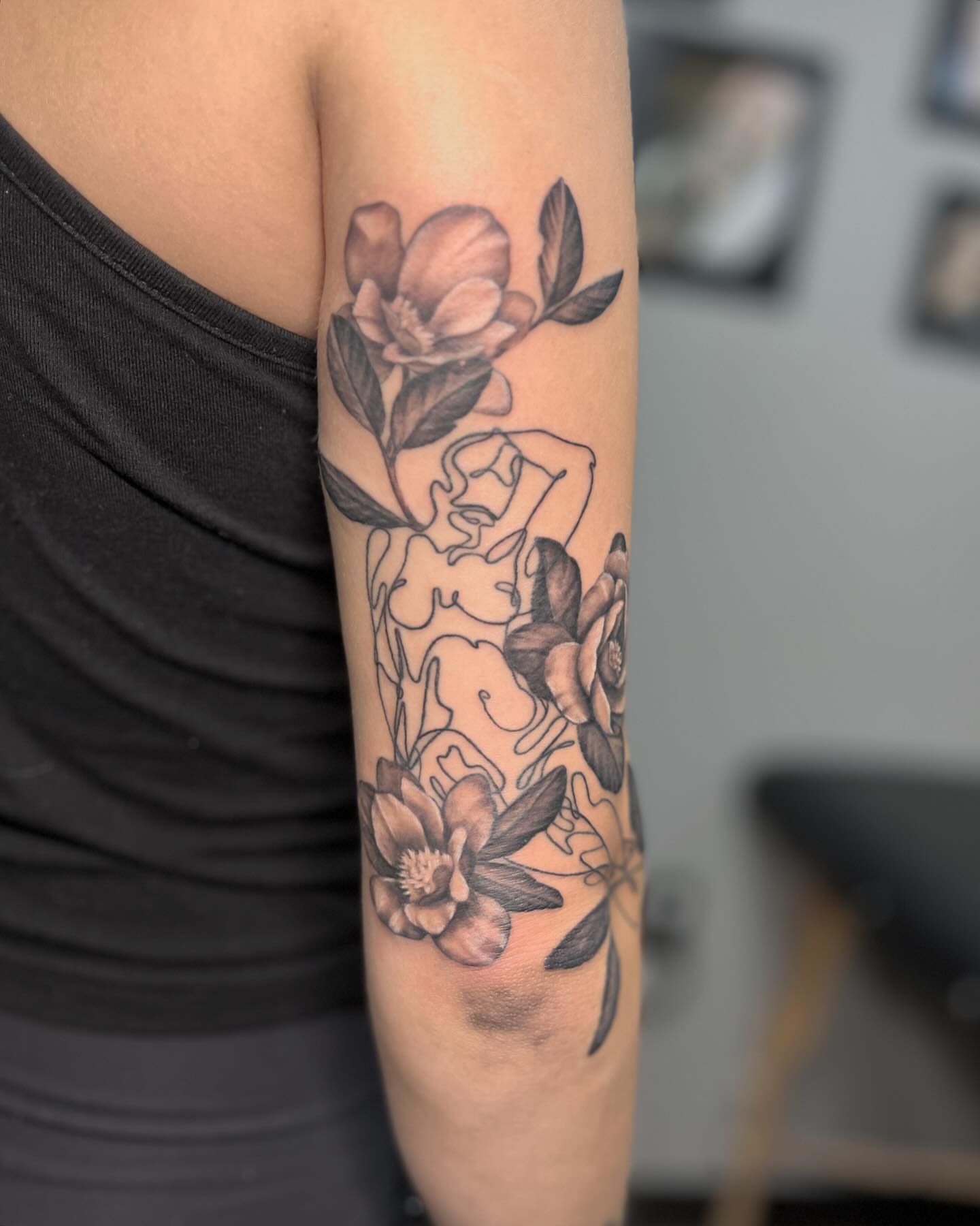 Floral and female figure realism tattoo on the forearm by Katlyne Jones