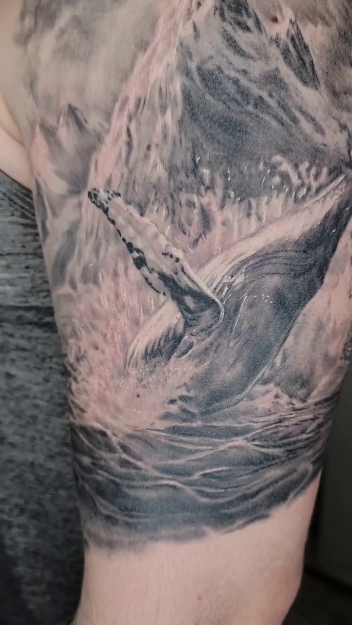Whale breaching in ocean waves realism tattoo by Zach Mullins