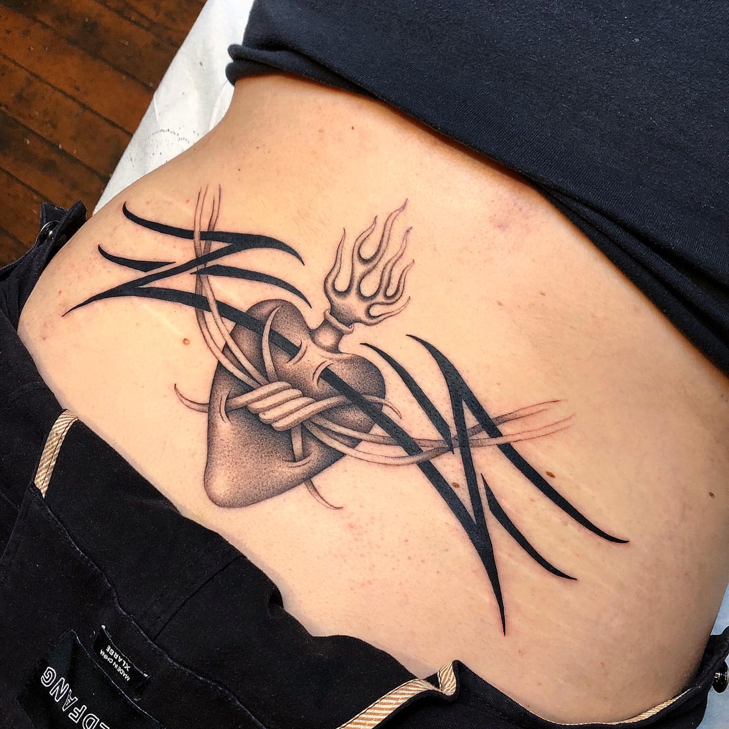 Heart with trident black and grey tattoo on the ribs by Mickey