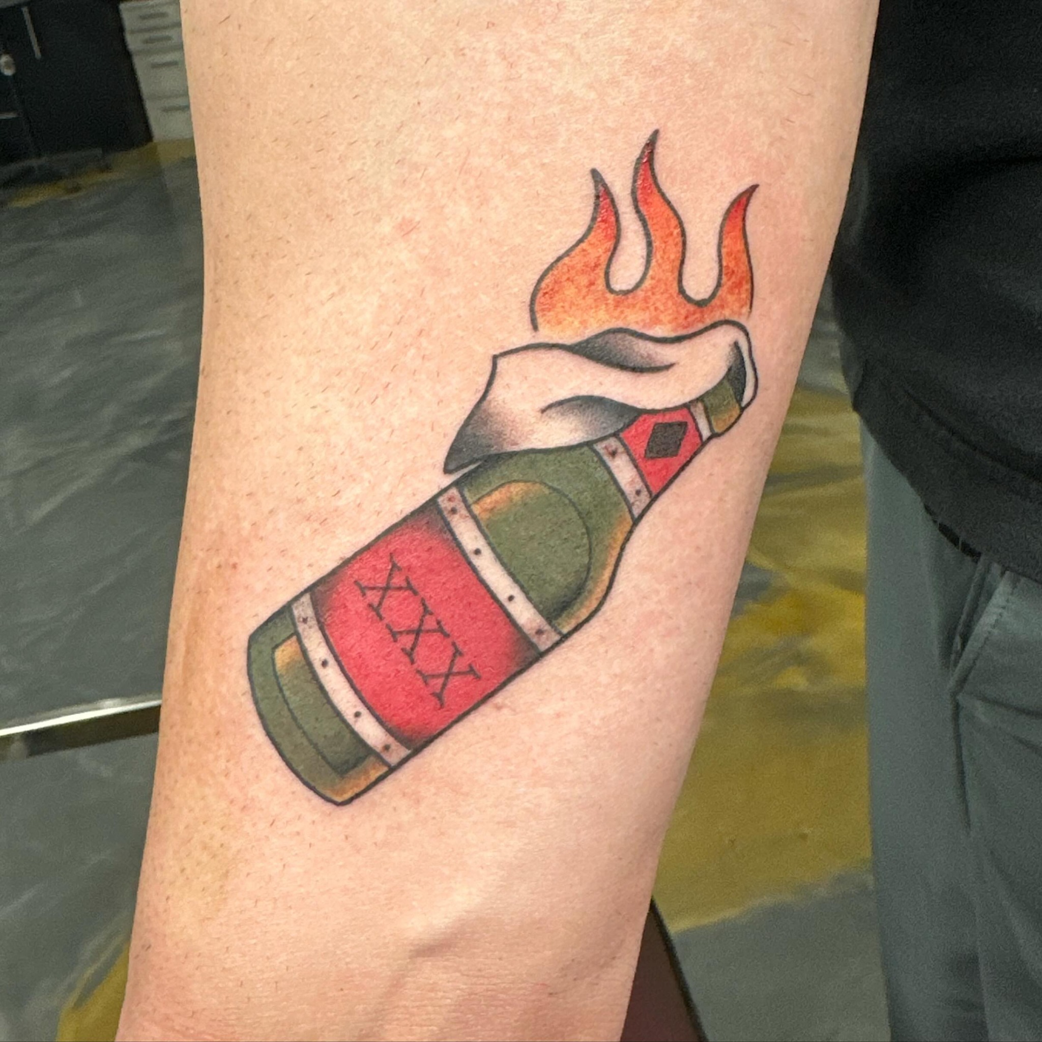 Burning bottle American traditional tattoo on the forearm by Christopher Heffley